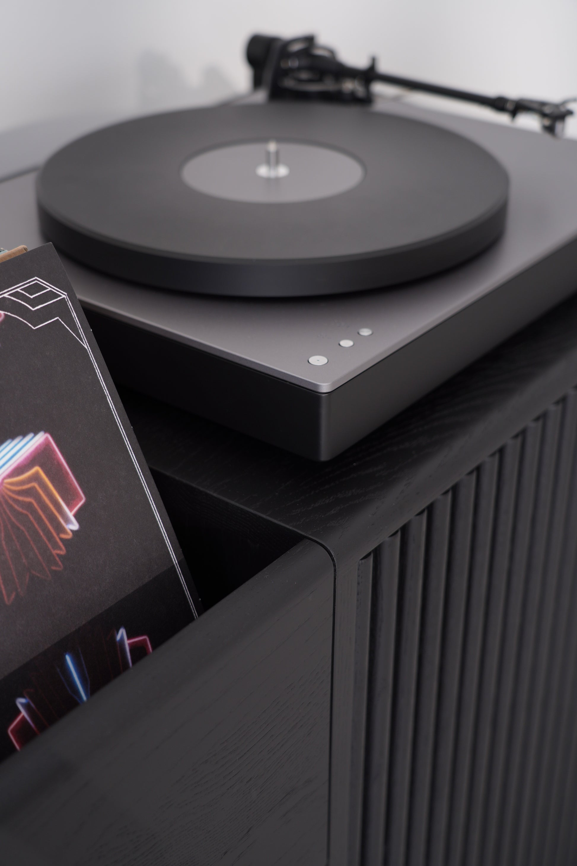 Sleek turntable with a black vinyl record and a colorful album cover nearby.