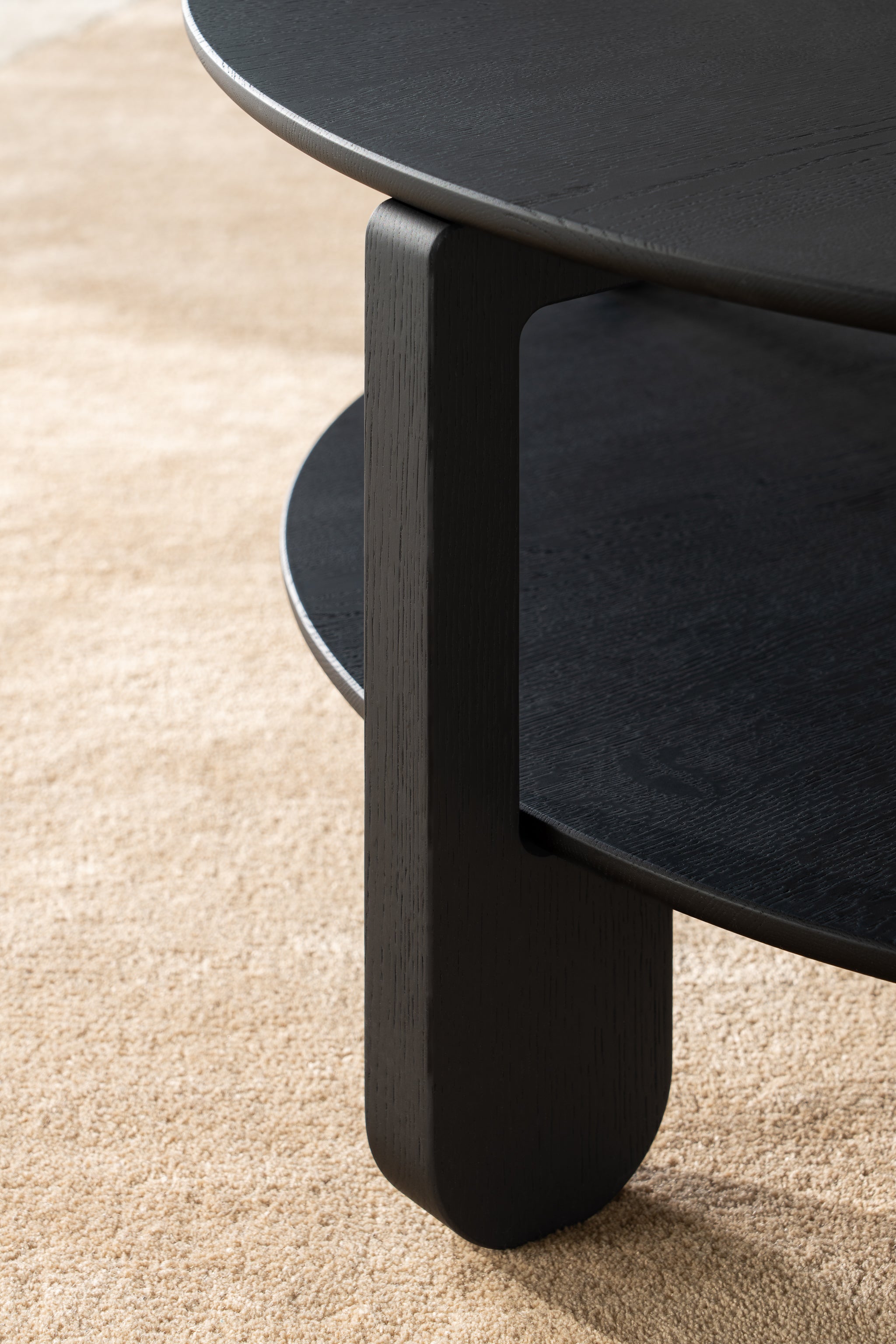 Top-down view of the NOON coffee table showing black-oiled oak grain on the round surface