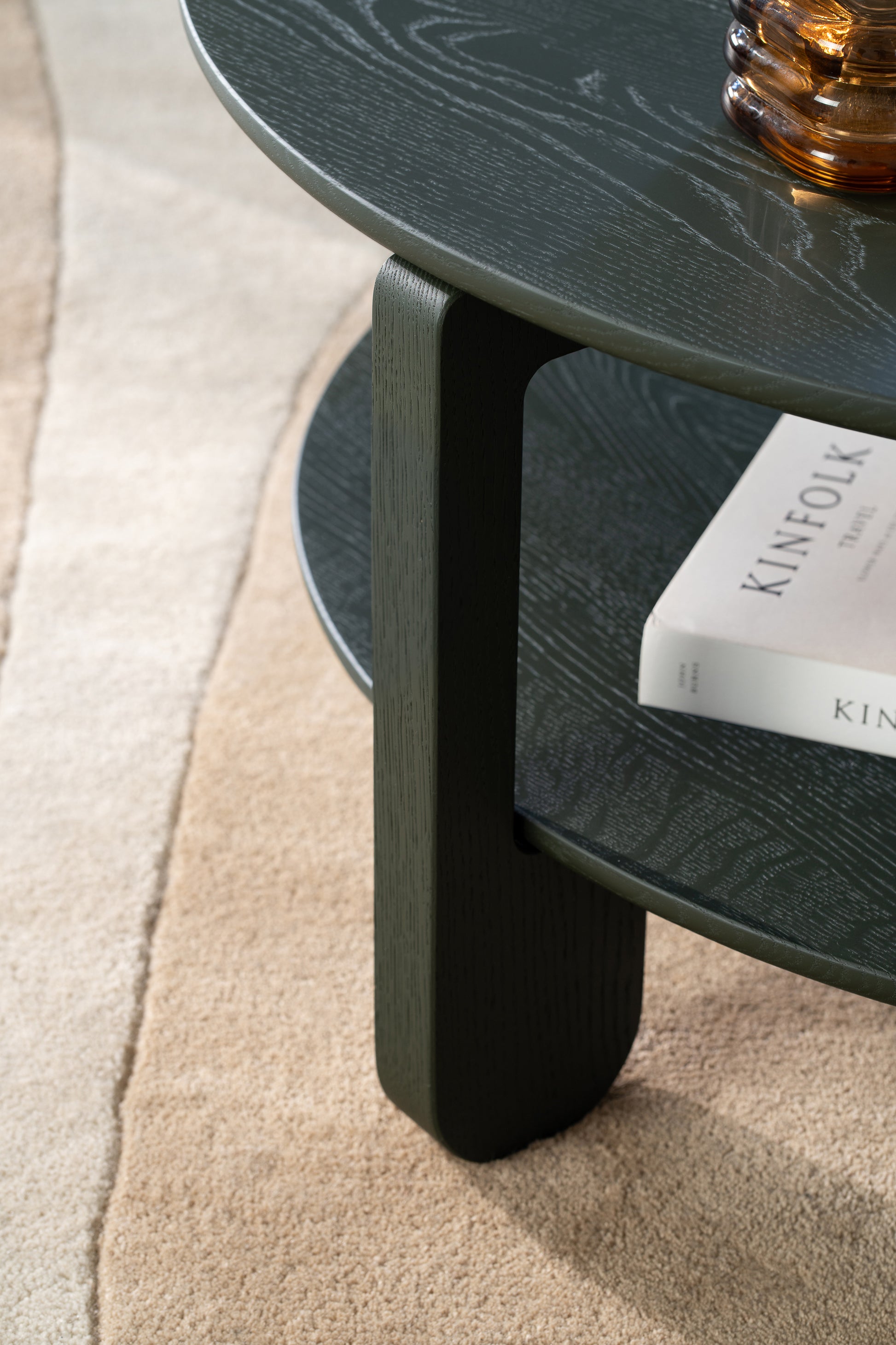 Side profile of the NOON coffee table showing the matte dark green finish on solid oak