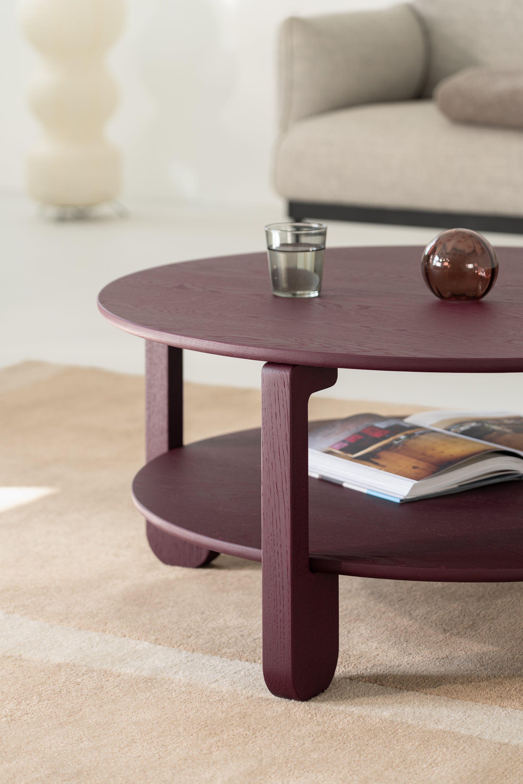 NOON burgundy round table styled in a living room with a neutral sofa and wool rug