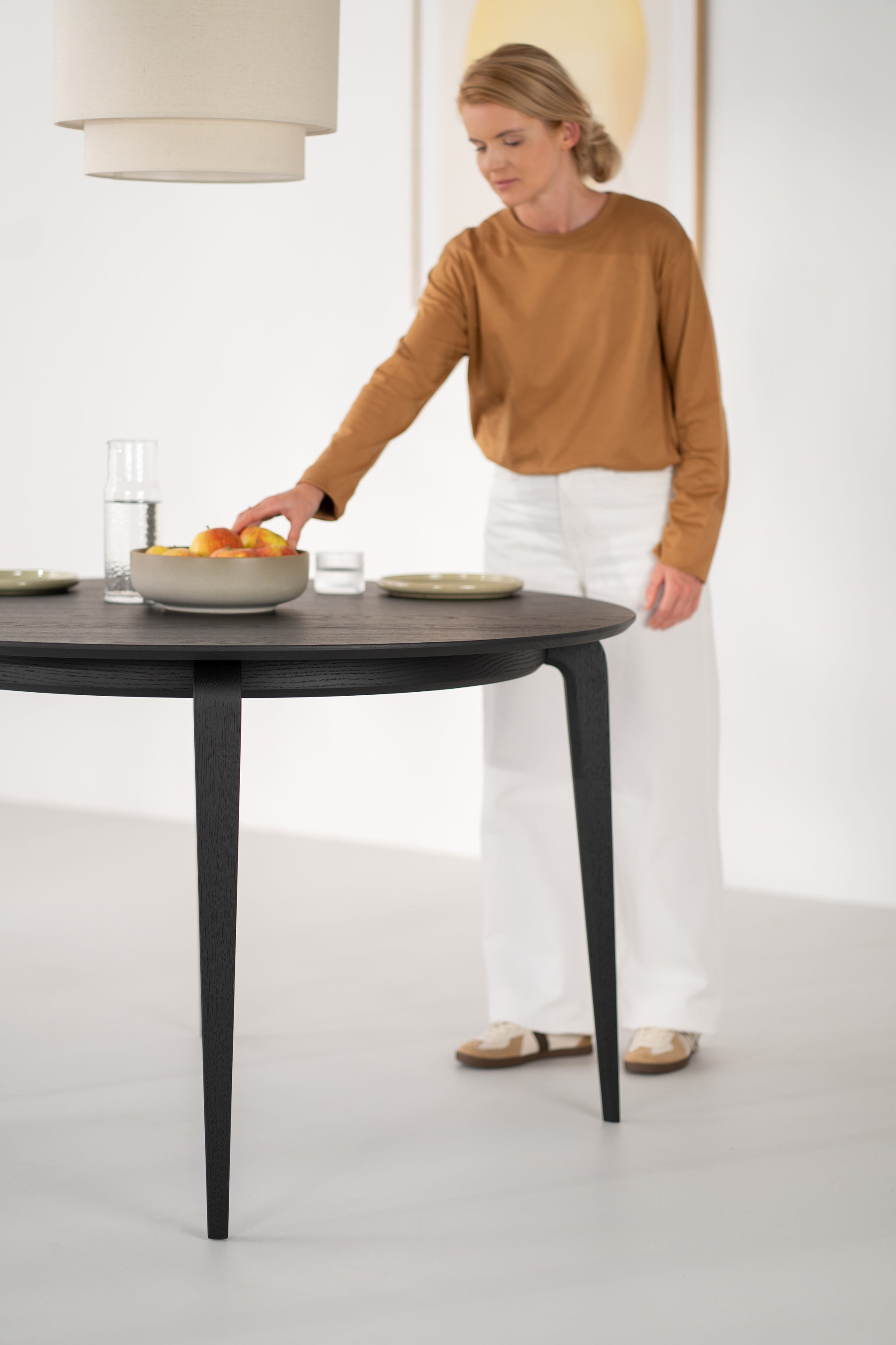 Mesa redonda YUKI en roble negro fotografiada en un salón con luz natural lateral