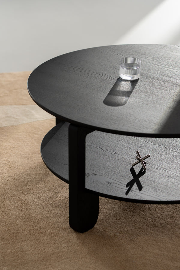 Angled view of the NOON table highlighting tapered legs and round tabletop in black oak