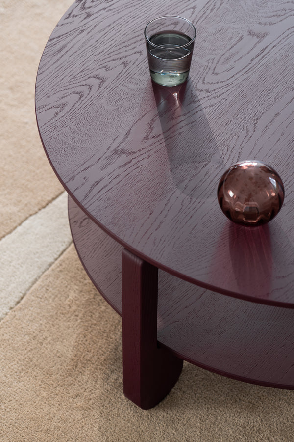 Angled view of the NOON coffee table highlighting the grain pattern beneath the burgundy coat