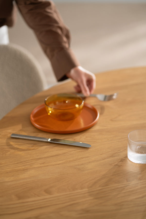 Person sitting at the YUKI round table, arm resting on the oiled oak surface.