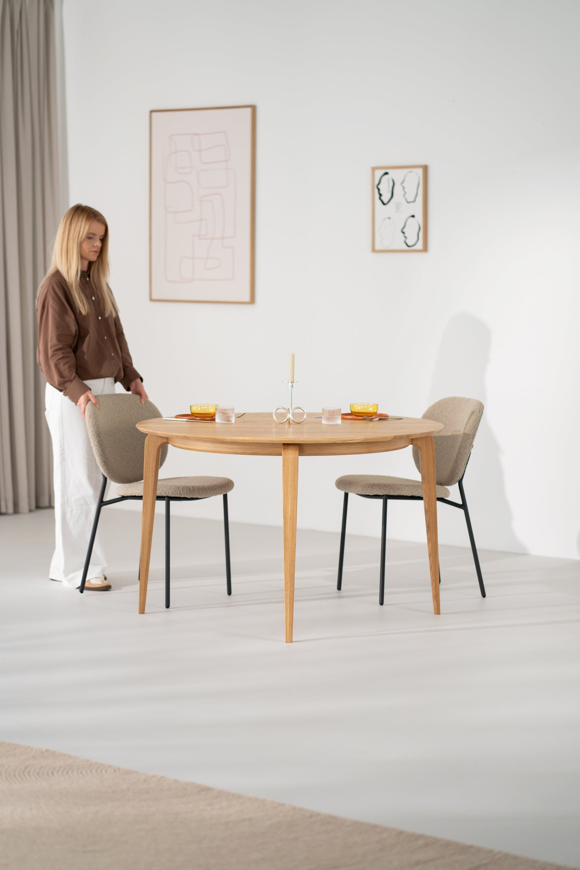 YUKI dining table in a bright room, two coffee cups on the oak surface near a window.