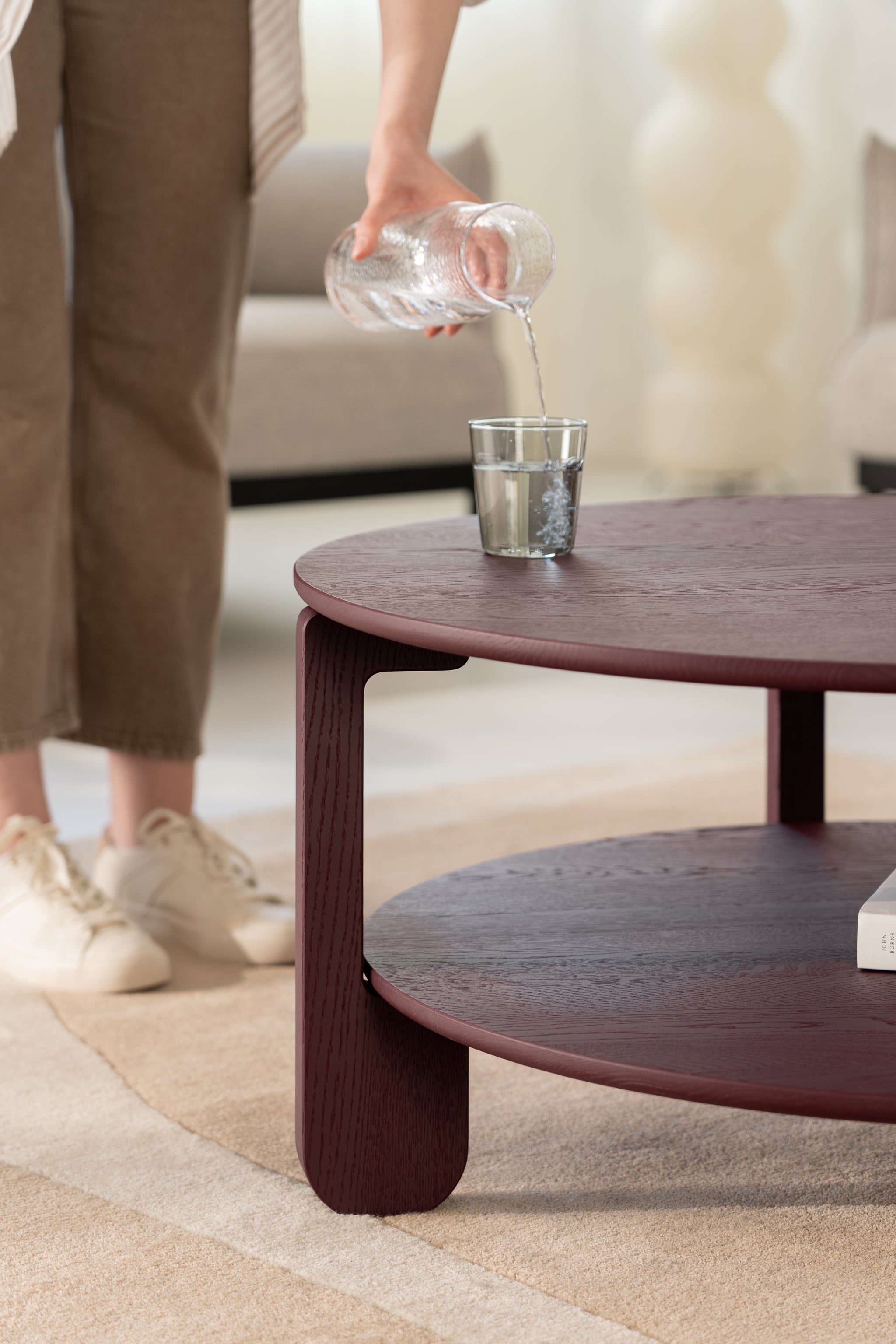 Detail of the NOON table leg joint where burgundy-finished oak meets the round tabletop