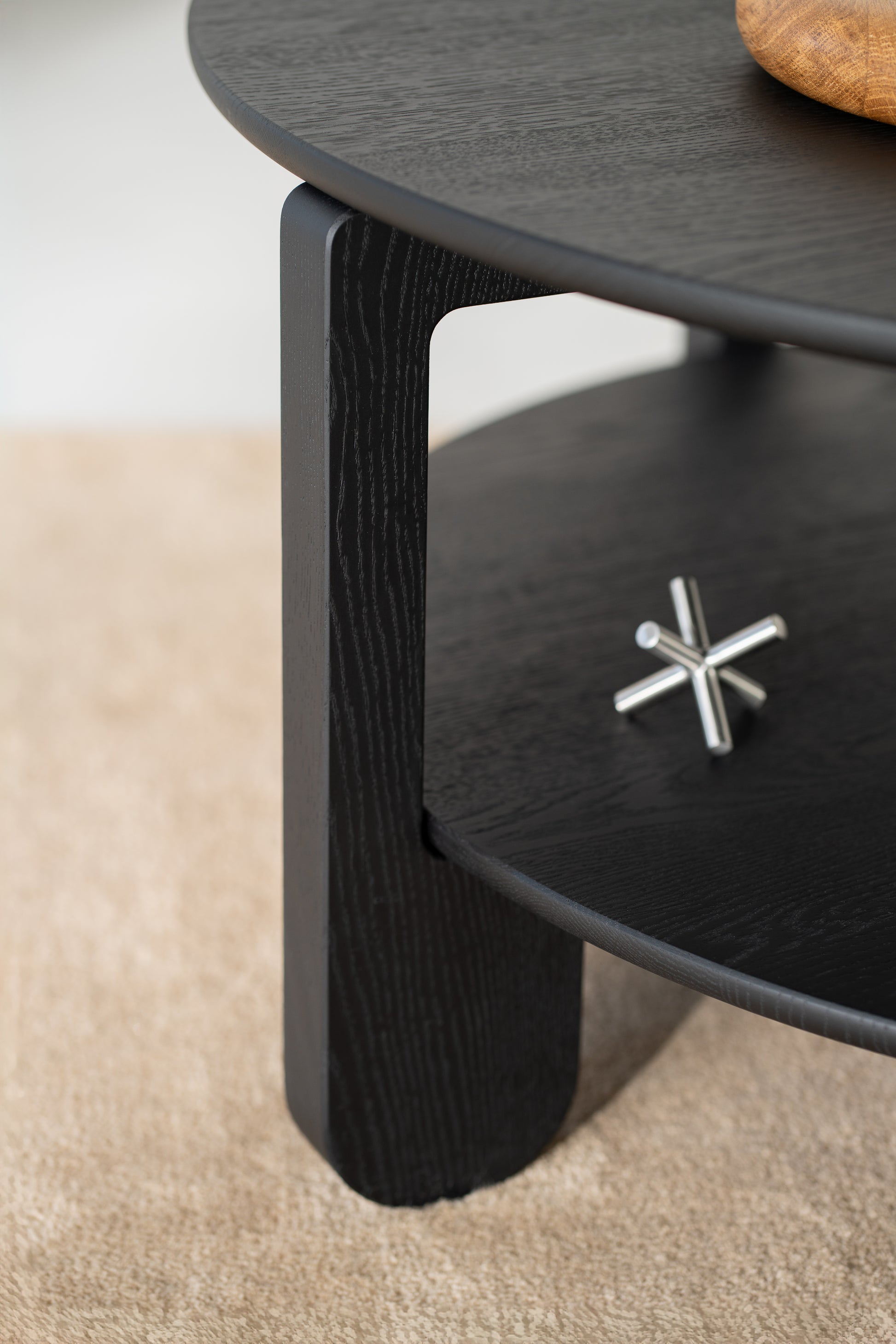 Side profile of the NOON round coffee table showing its low silhouette and gentle curves