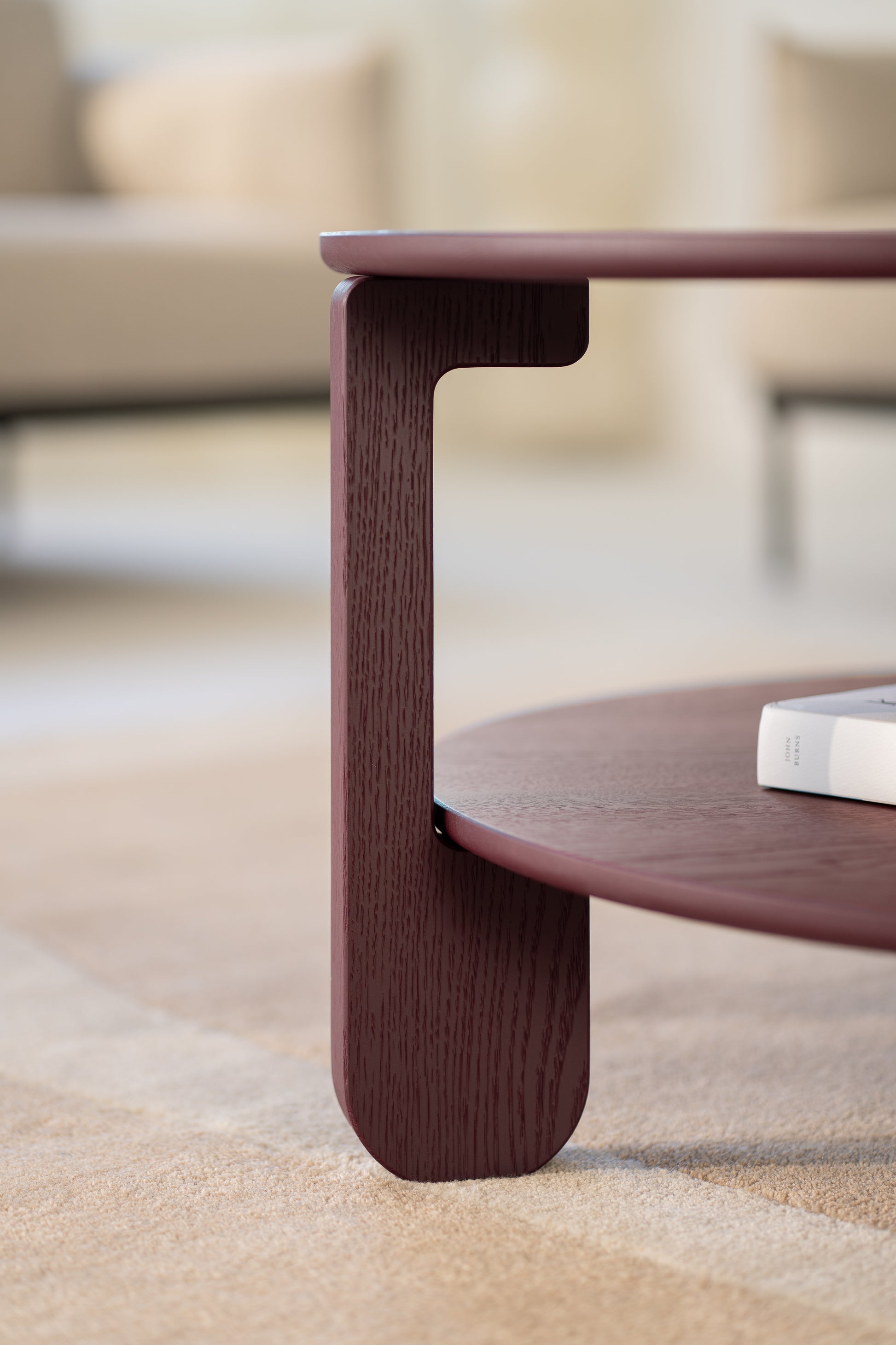 Top-down view of the NOON round coffee table with a ceramic cup and open book on the surface