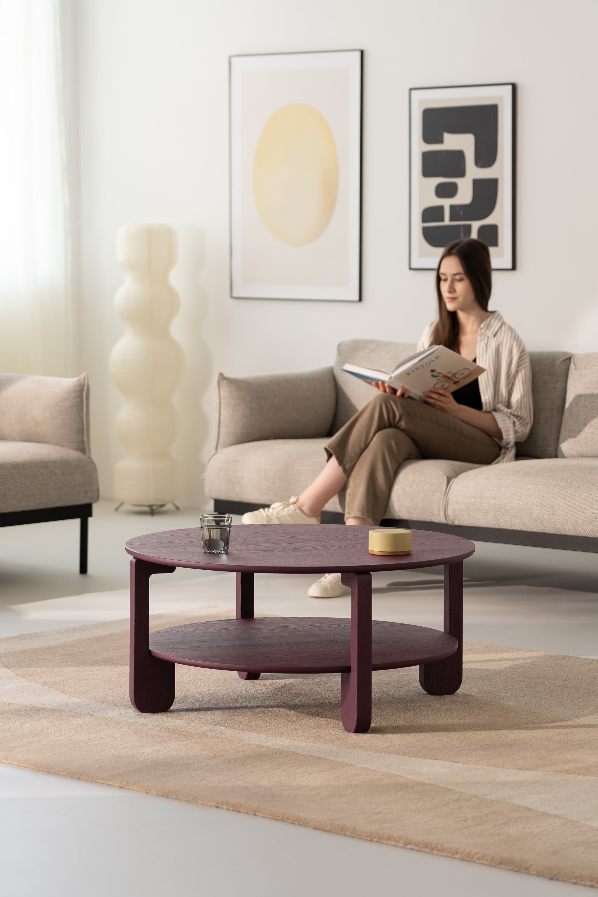 NOON burgundy coffee table placed on a concrete floor next to a mid-century armchair