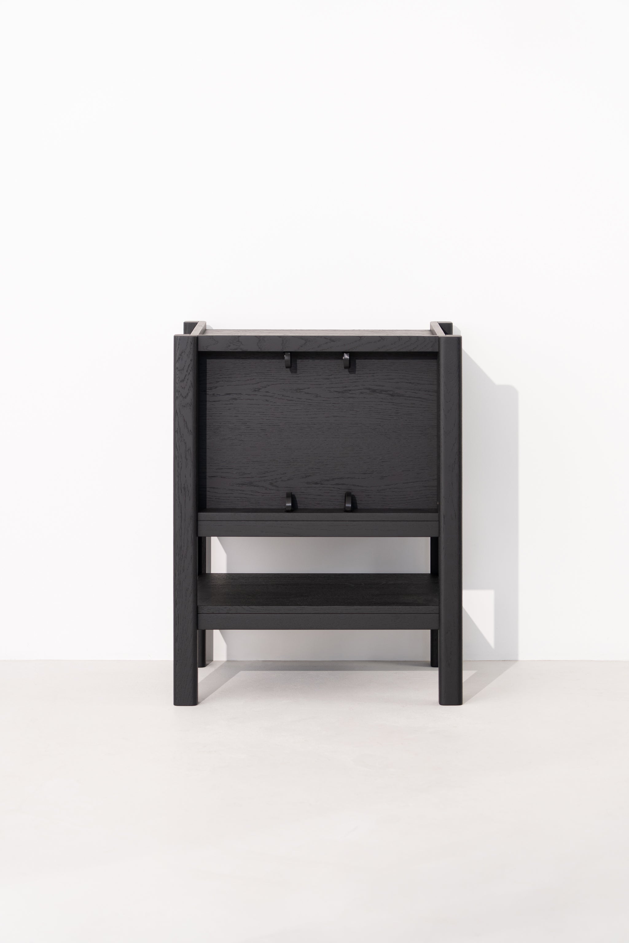 Black wooden chair folded flat against a white wall.