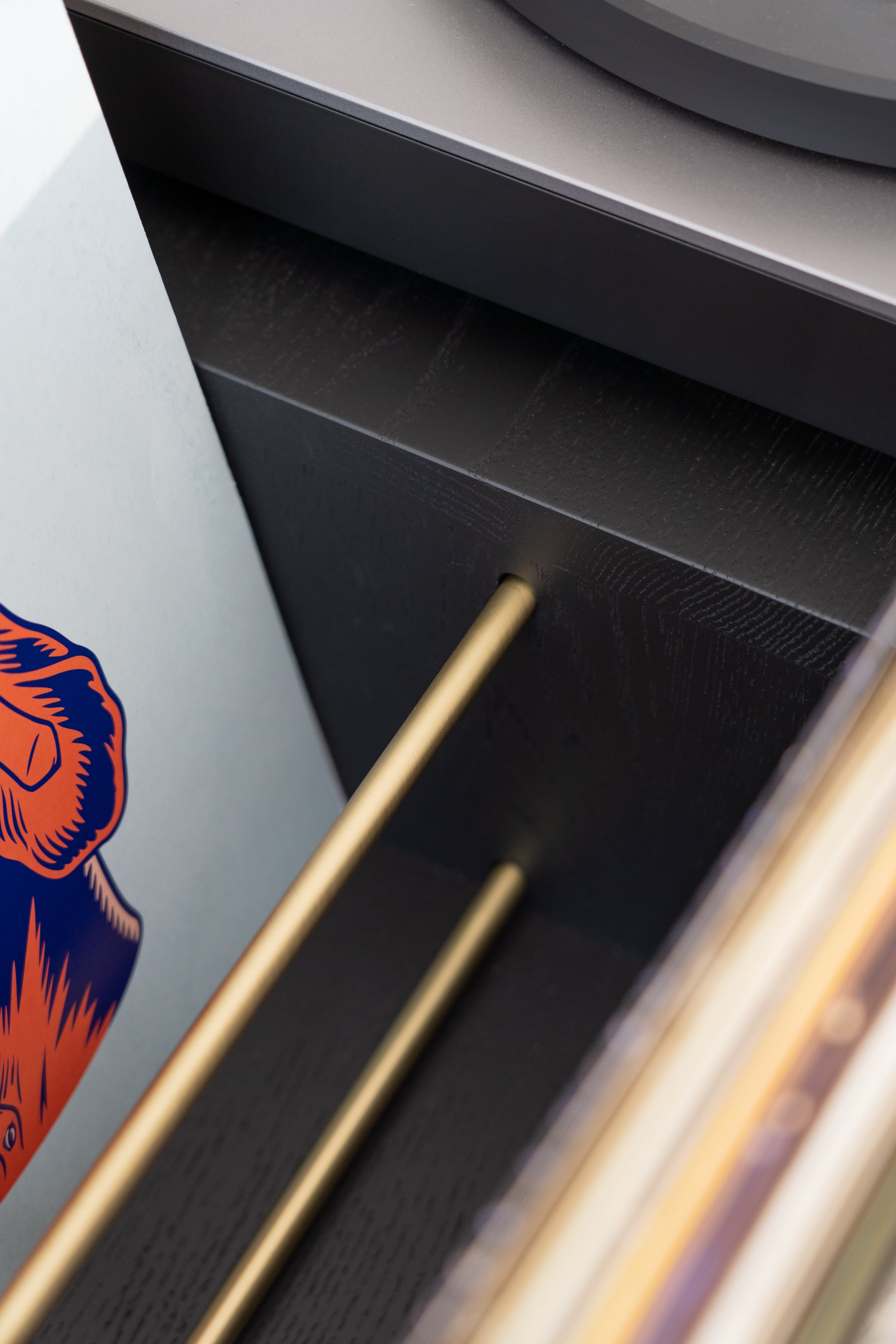 Close-up of a drawer with golden rods and a colorful abstract design on one side.