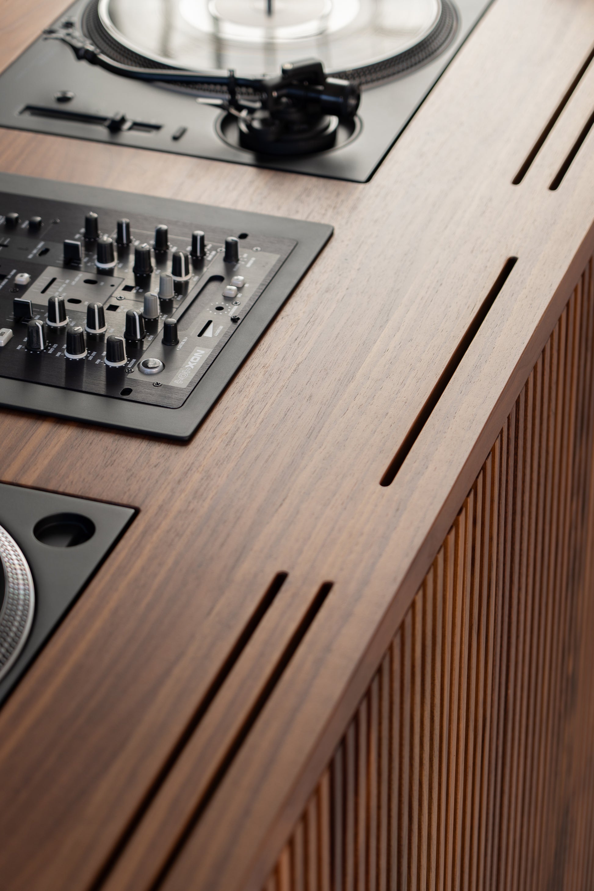 Close-up of a DJ setup on a wooden surface, featuring a mixer and turntable with vinyl record.
