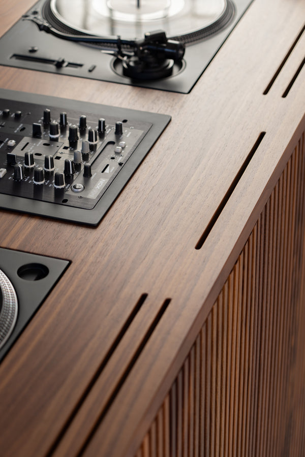 Close-up of a DJ setup on a wooden surface, featuring a mixer and turntable with vinyl record.