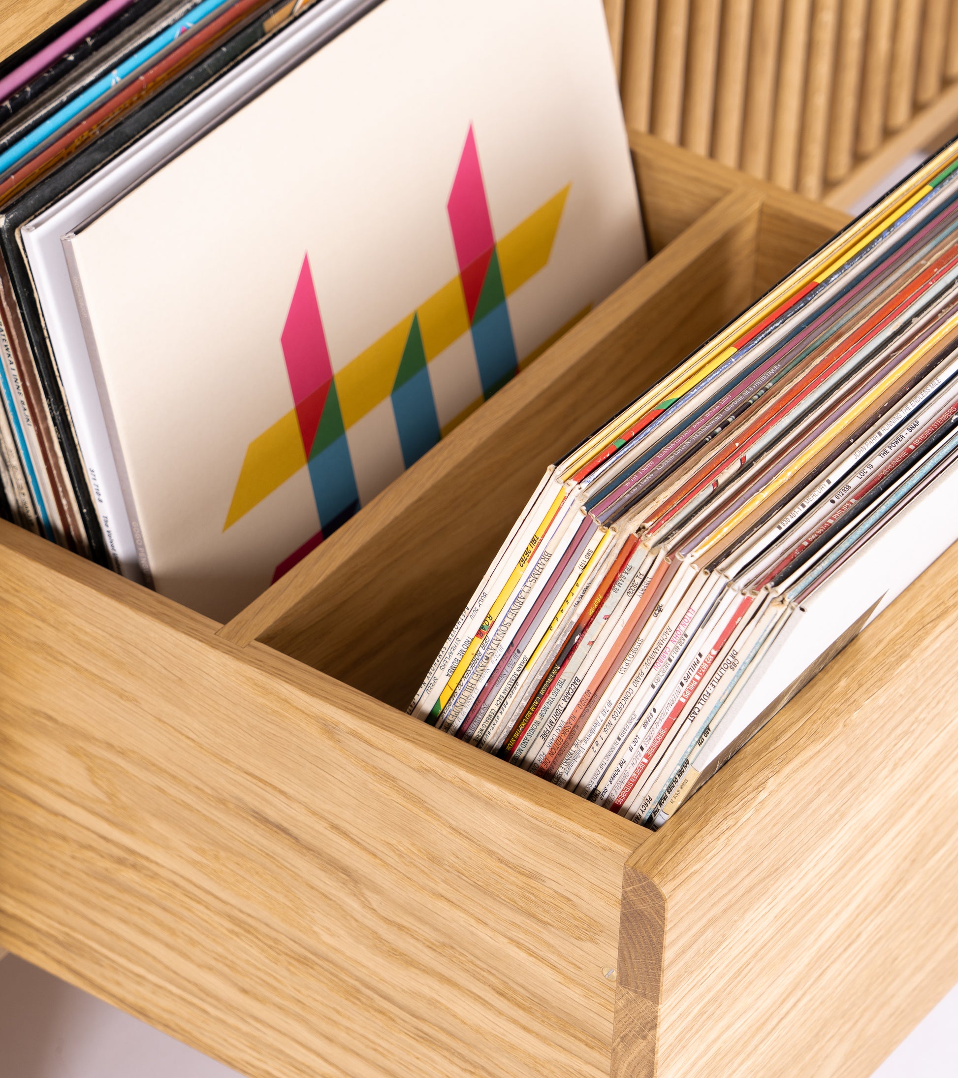 A wooden box with colorful vinyl records and a cover featuring a geometric pattern.
