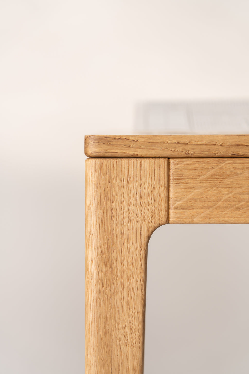 A close-up of the corner of a wooden table with rounded edges.
