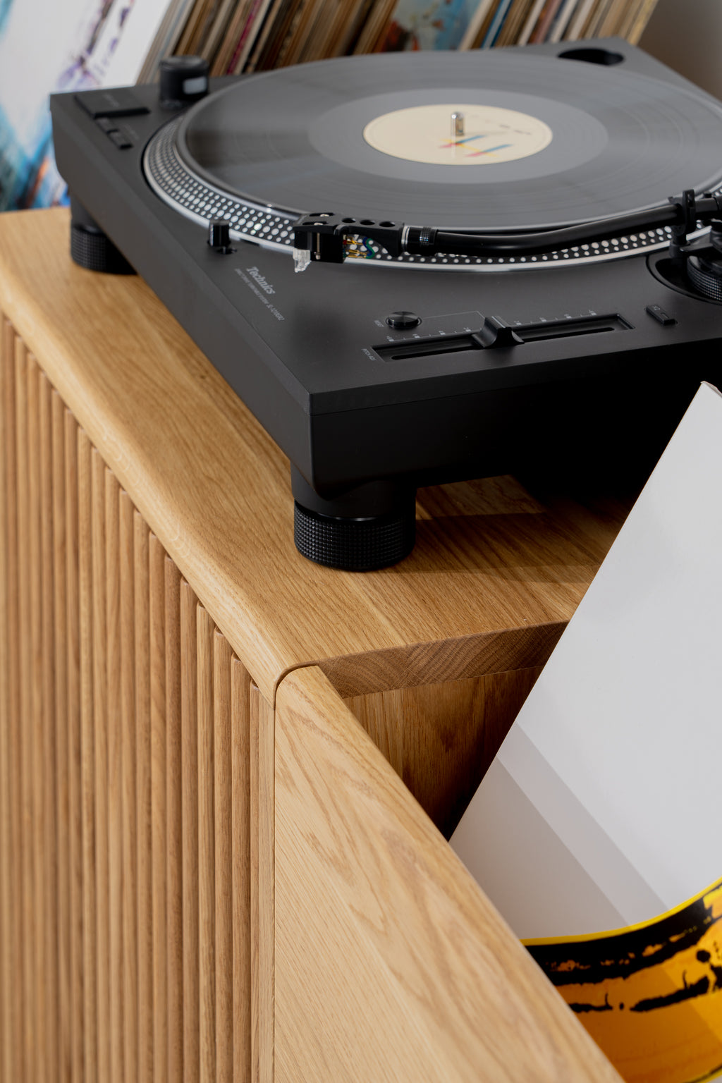 FUSE X in solid oak, rounded top corner beneath a black turntable, with a sleeve leaning out of the record compartment