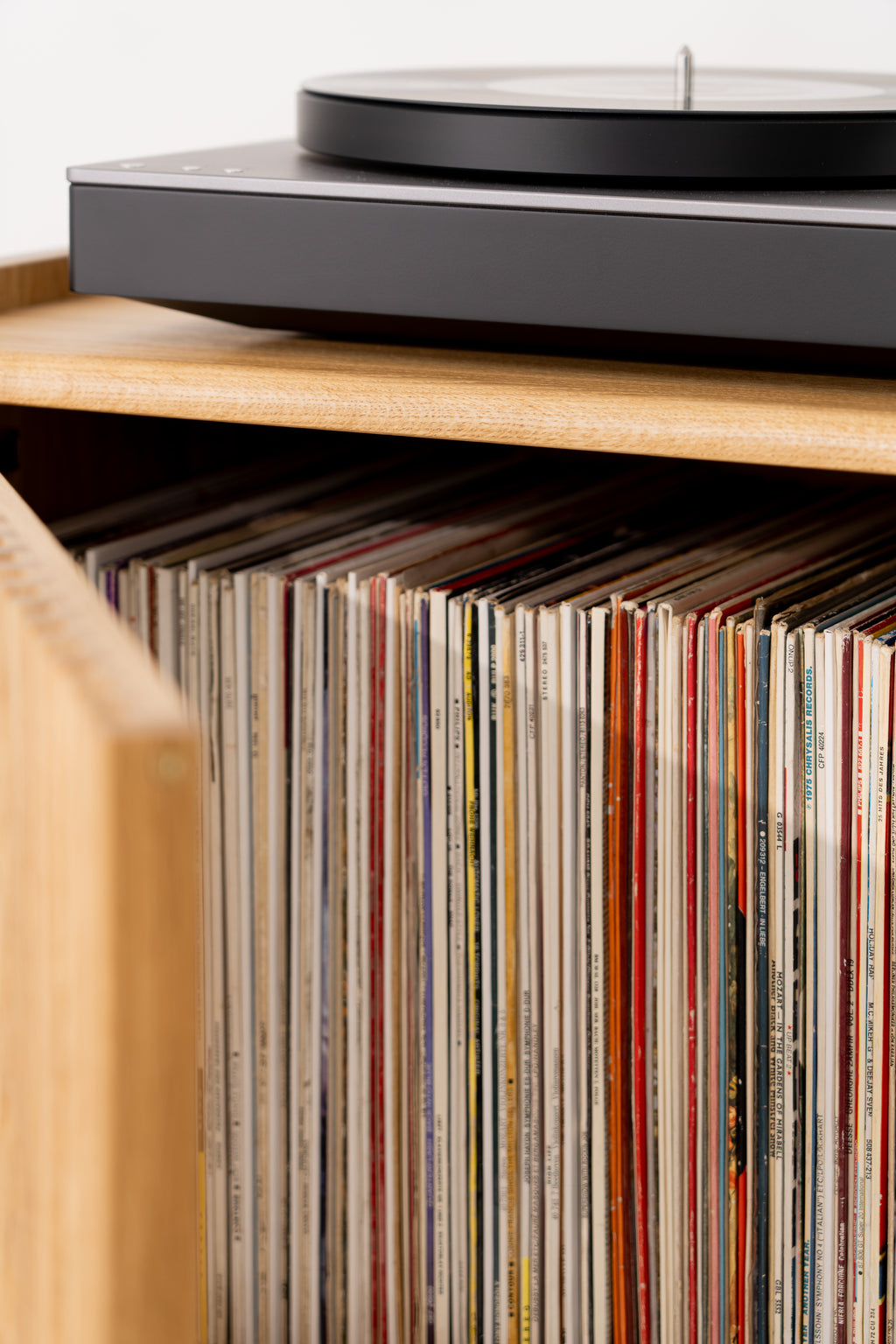 Vinyl records neatly stored inside a solid oak cabinet.