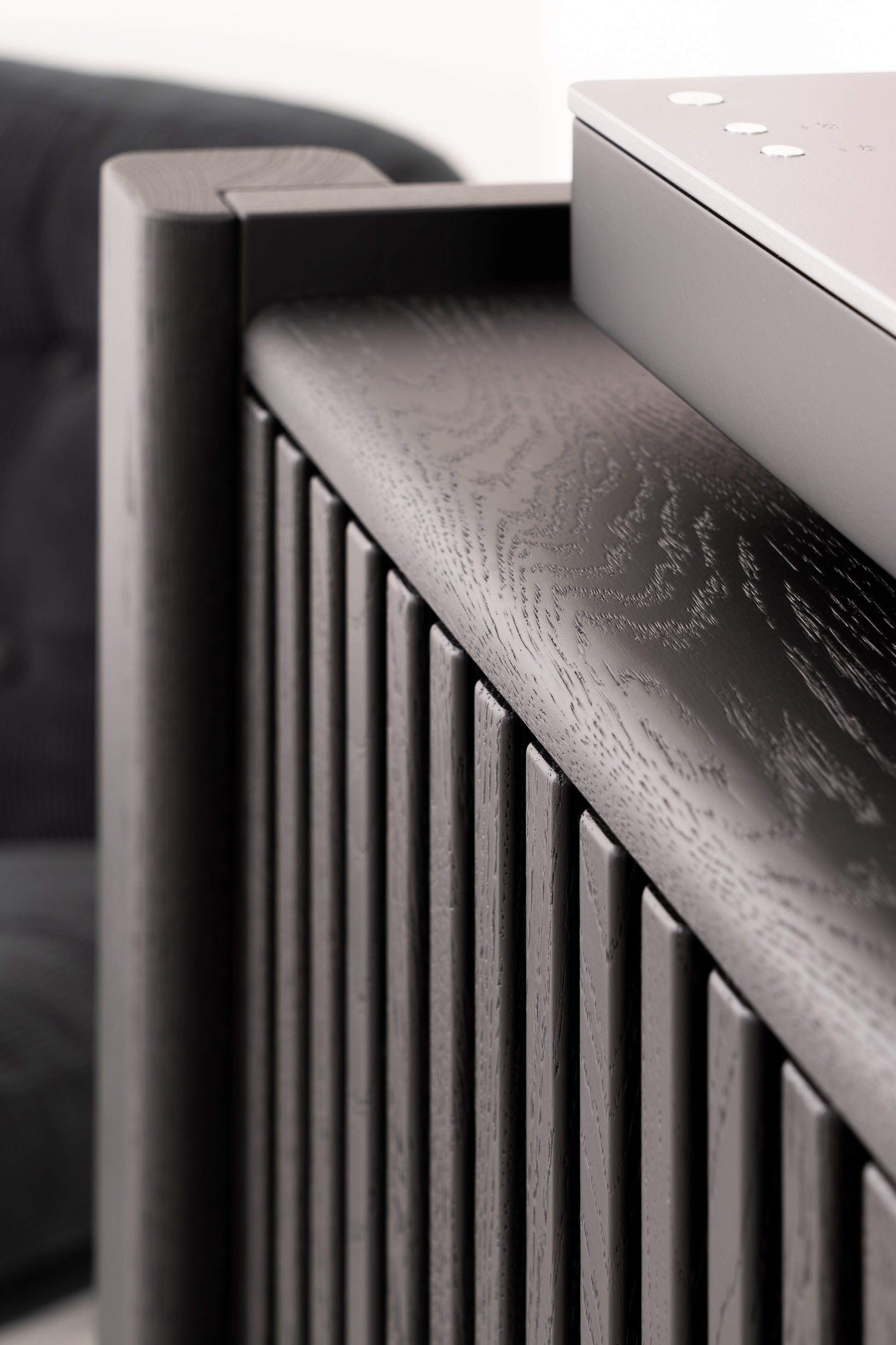 Close-up of a modern, dark wood slatted design with a smooth metallic surface on top.