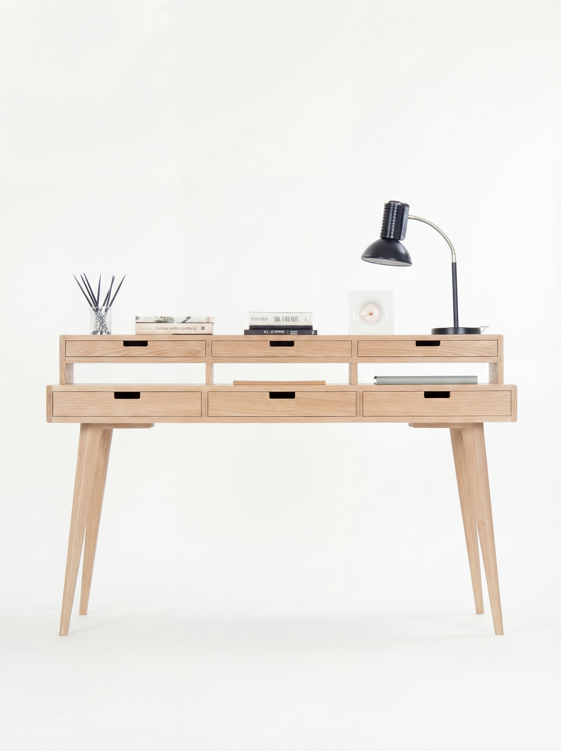 Minimalist wooden desk with six drawers, a table lamp, books, and a diffuser.