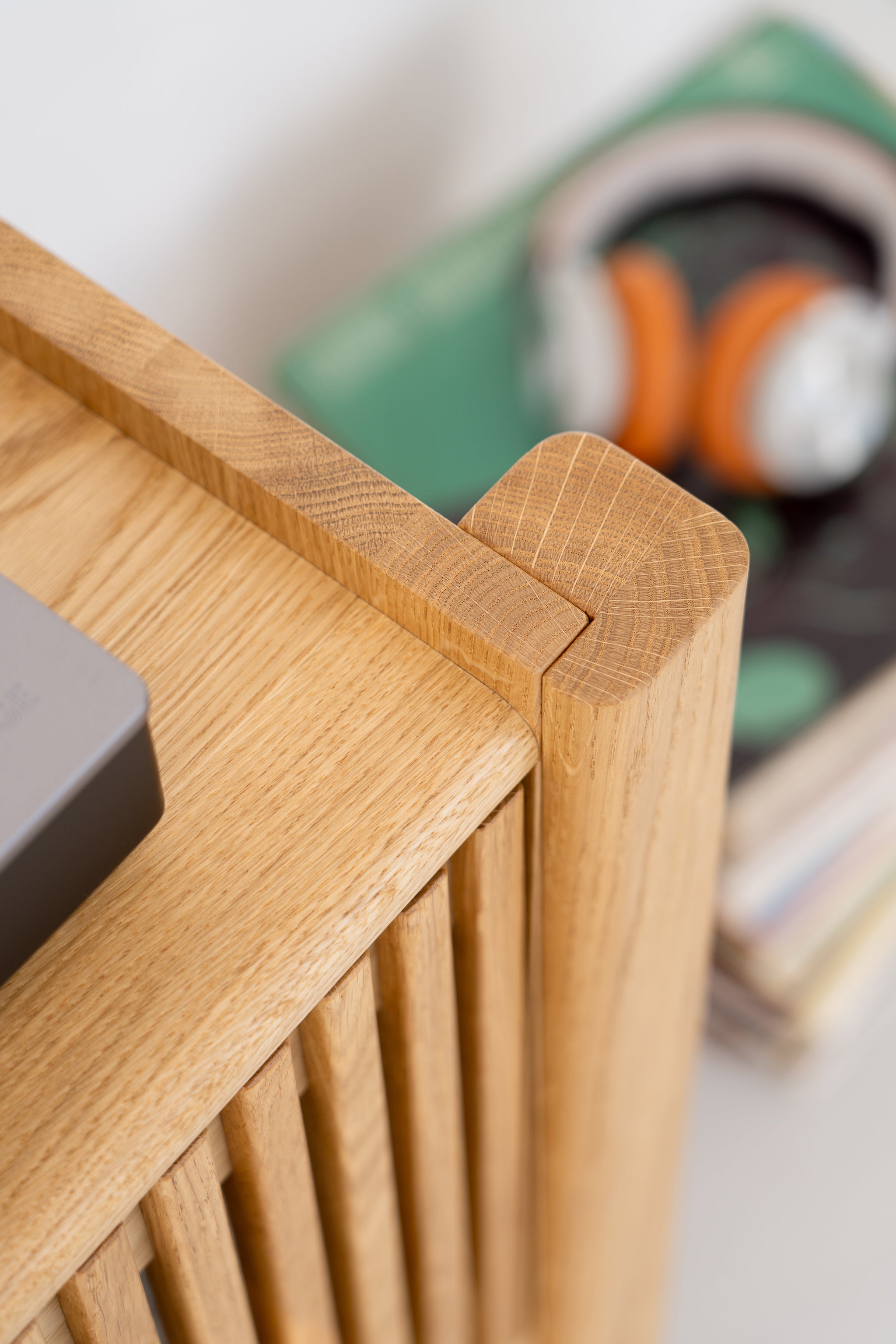 Close-up of a wooden cabinet corner with headphones and books blurred in the background.