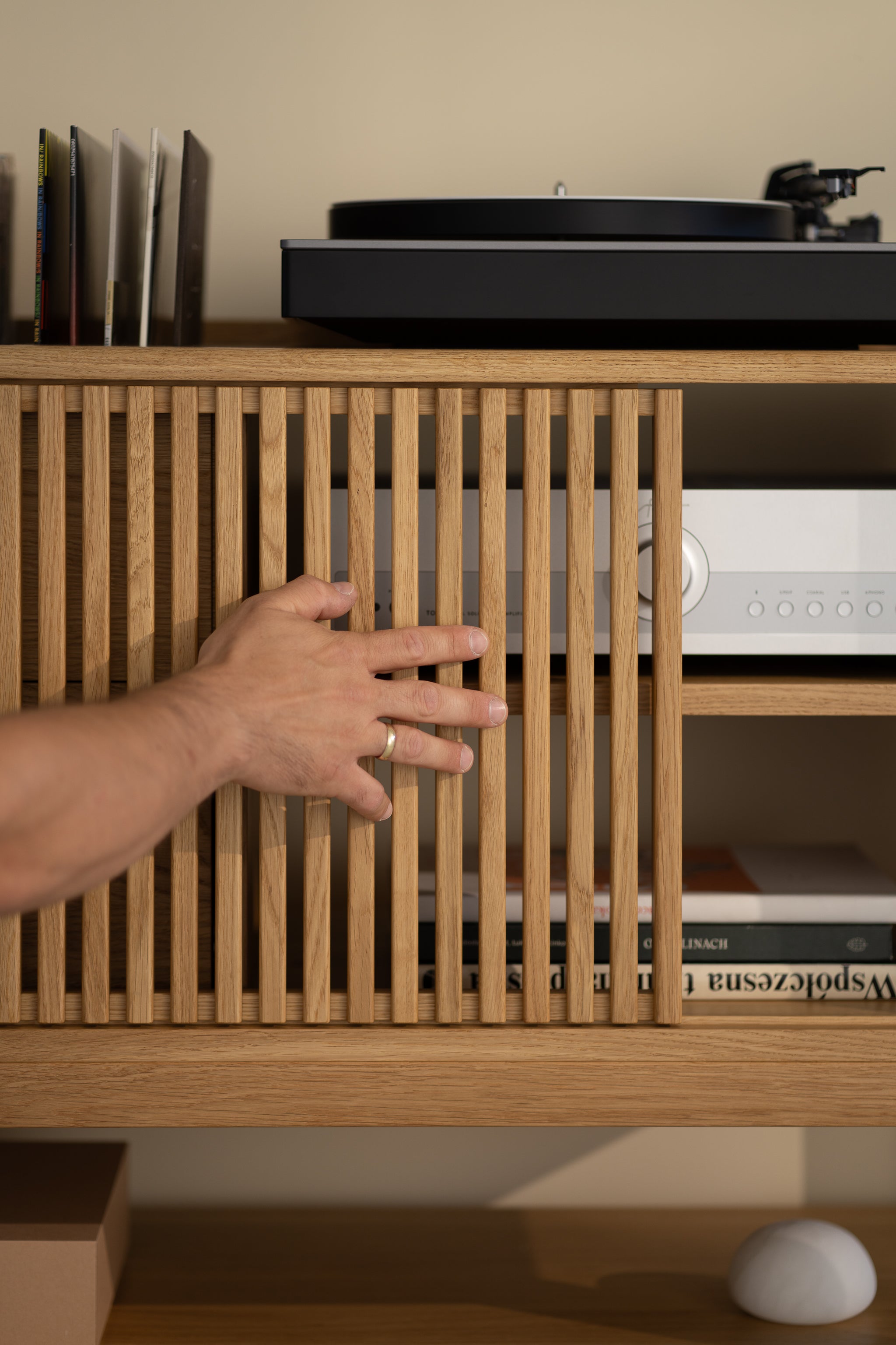 Hand opening slatted wooden cabinet door, revealing records and audio equipment inside.