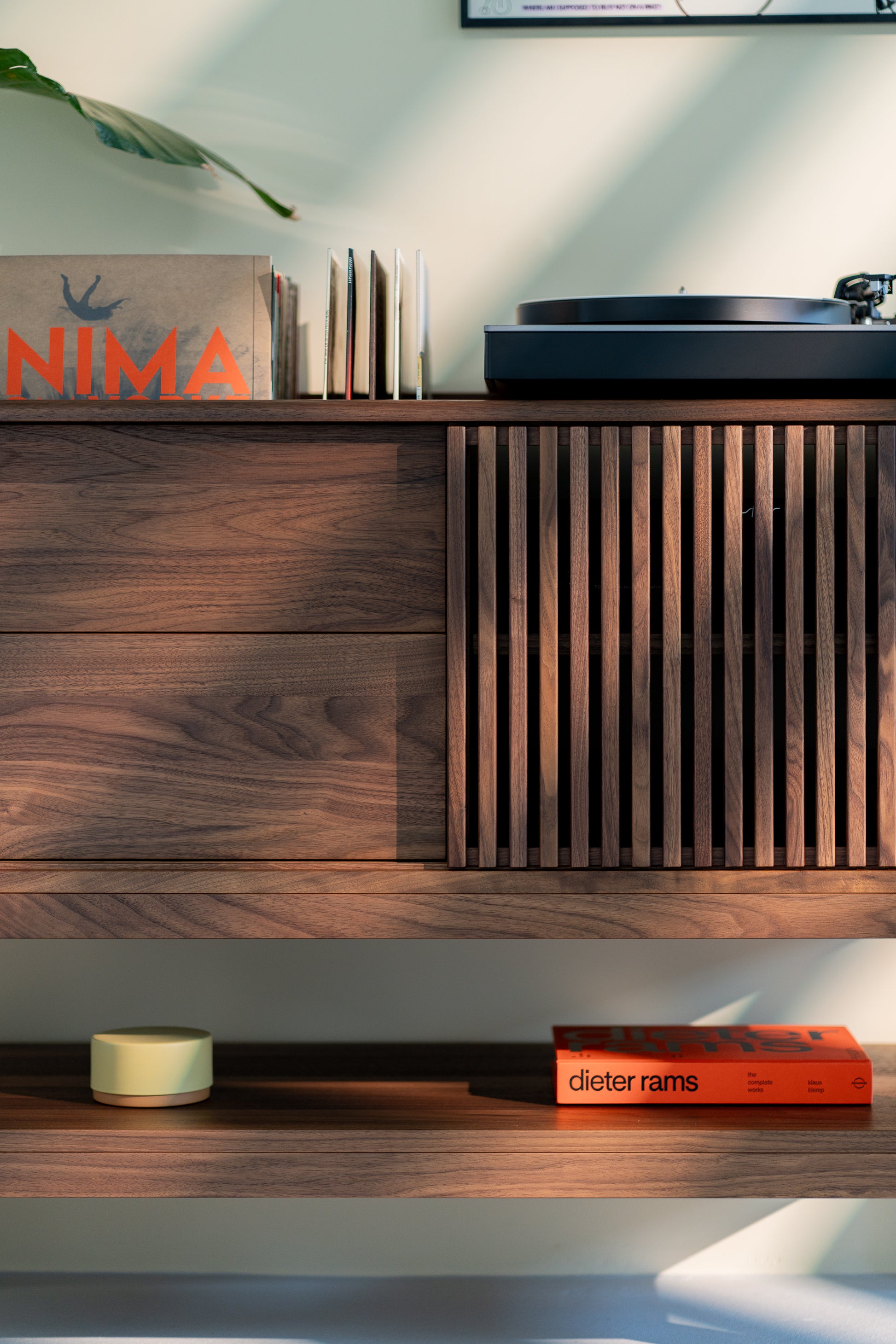 Wooden cabinet with records, a turntable, and a book titled "dieter rams" on the shelf below.