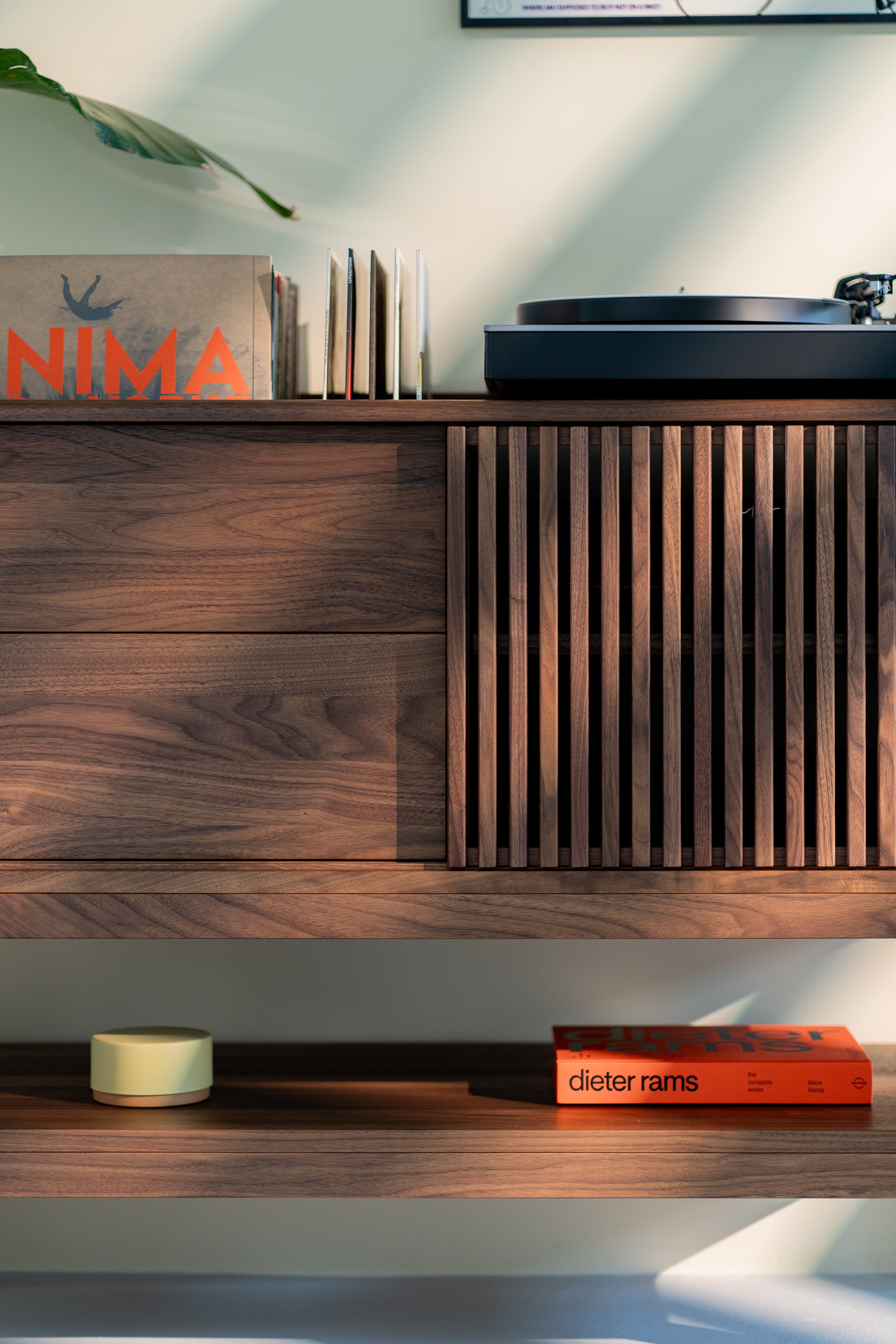 Wooden cabinet with records, a turntable, and a book titled "dieter rams" on the shelf below.