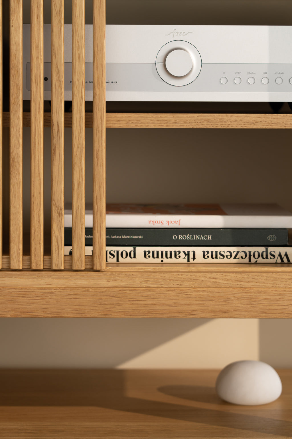 Wooden shelf with a stereo, books, and a white decorative stone.