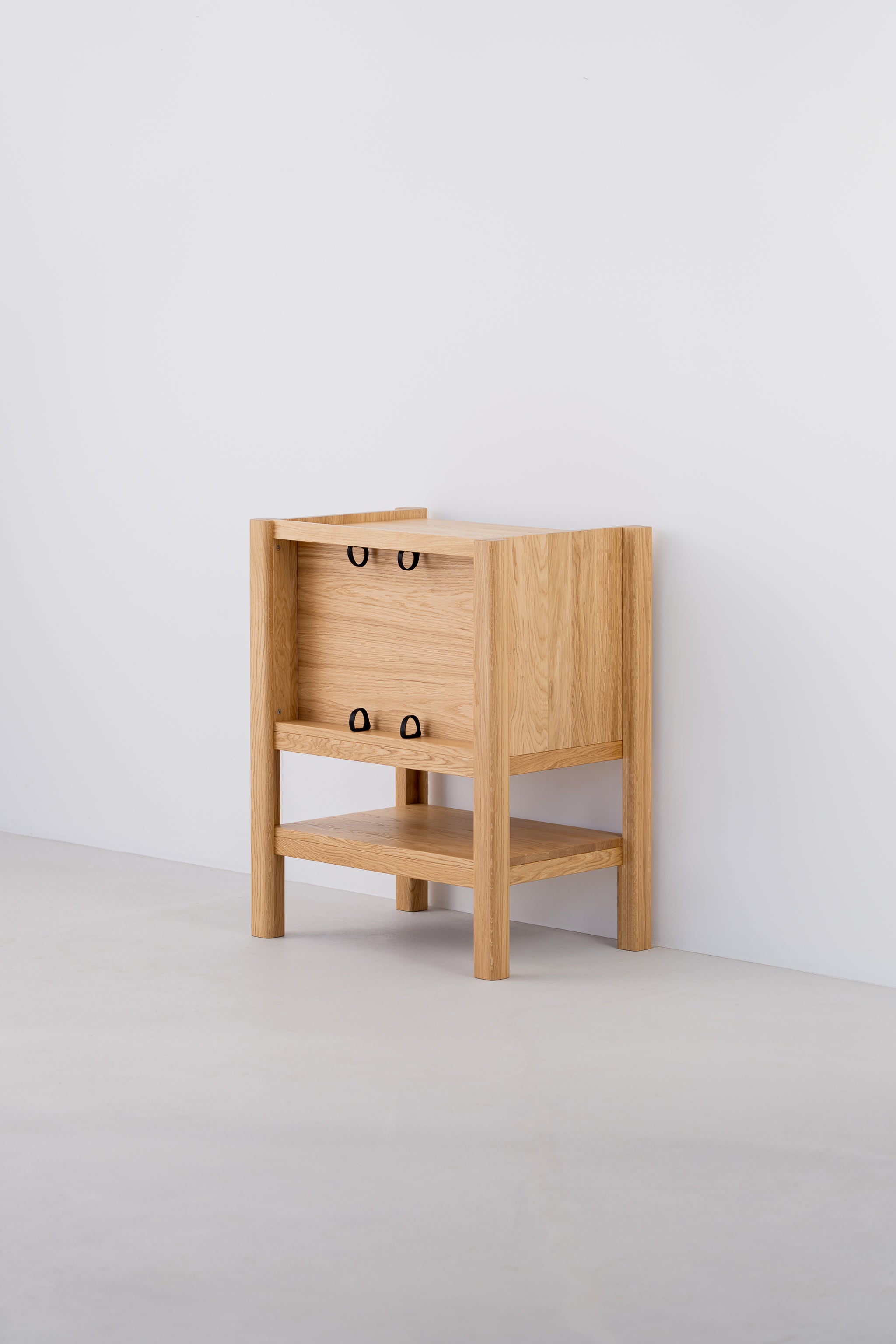 Wooden side table with open shelf and minimalist design against a white wall.