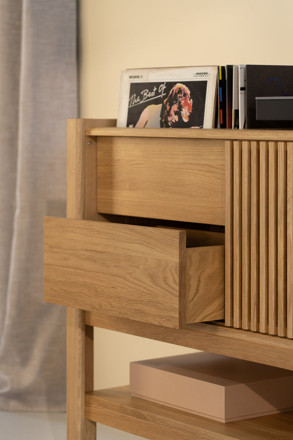 Open wooden drawer with records on top, beside a closed cabinet, and a box on the shelf below.