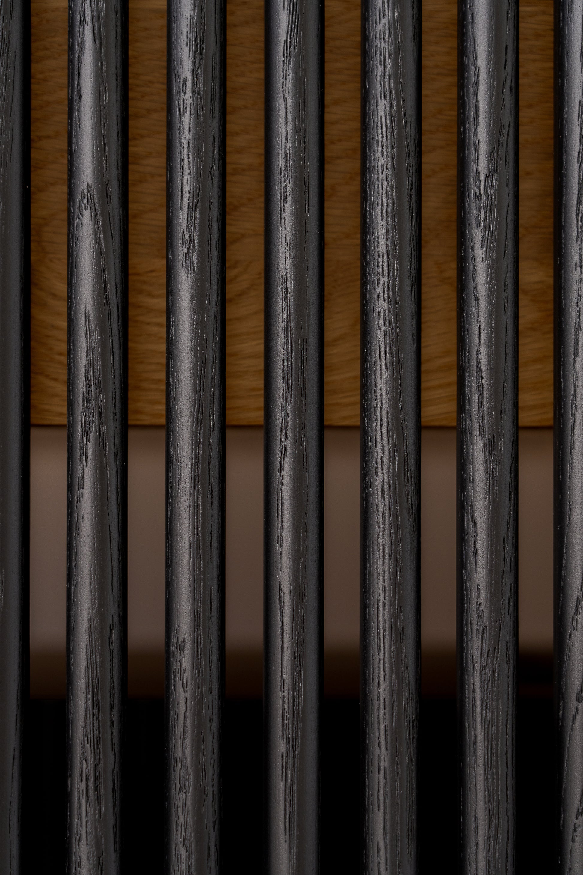 Close-up of vertical black bars with wood and a beige background.