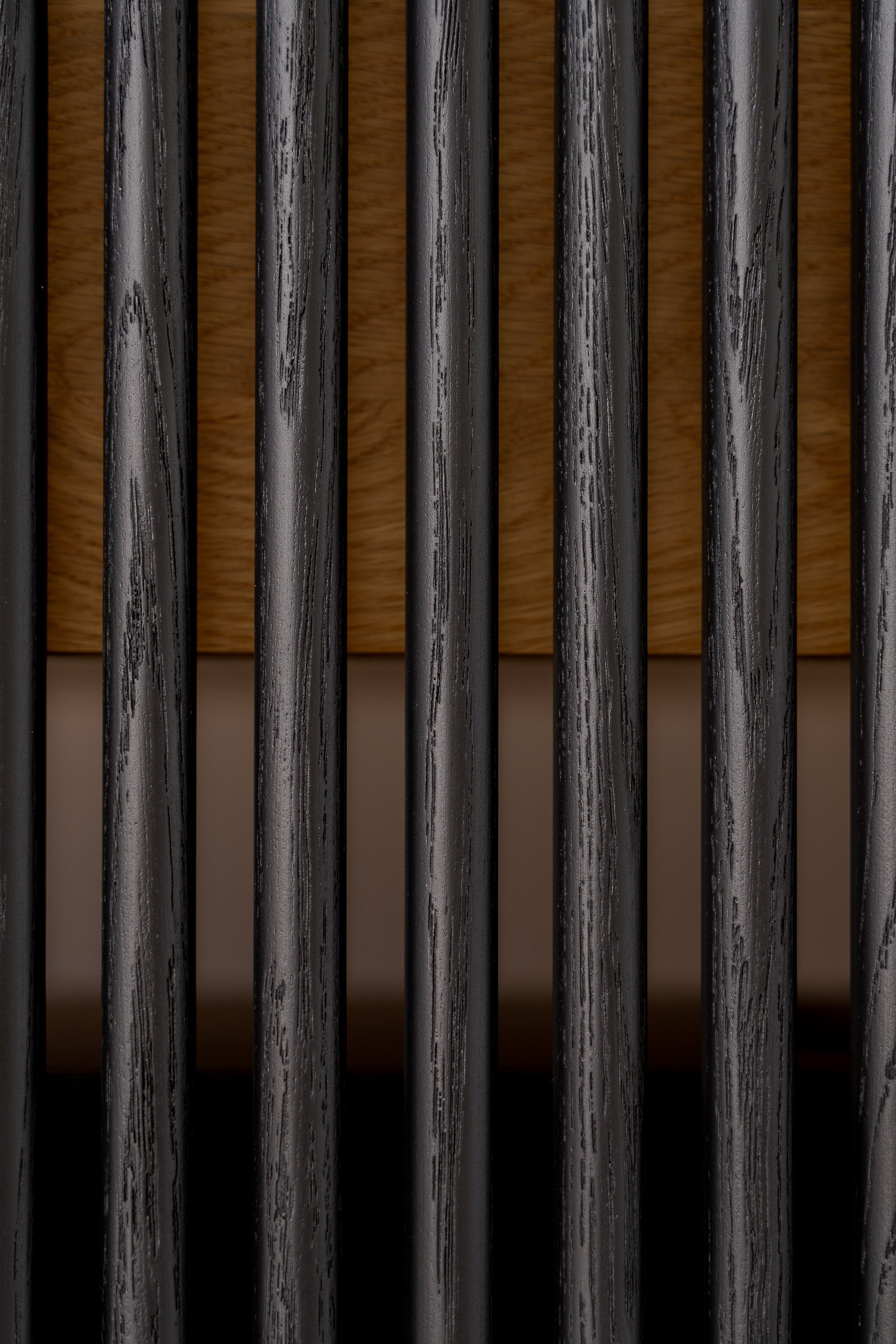 Close-up of vertical black bars with wood and a beige background.