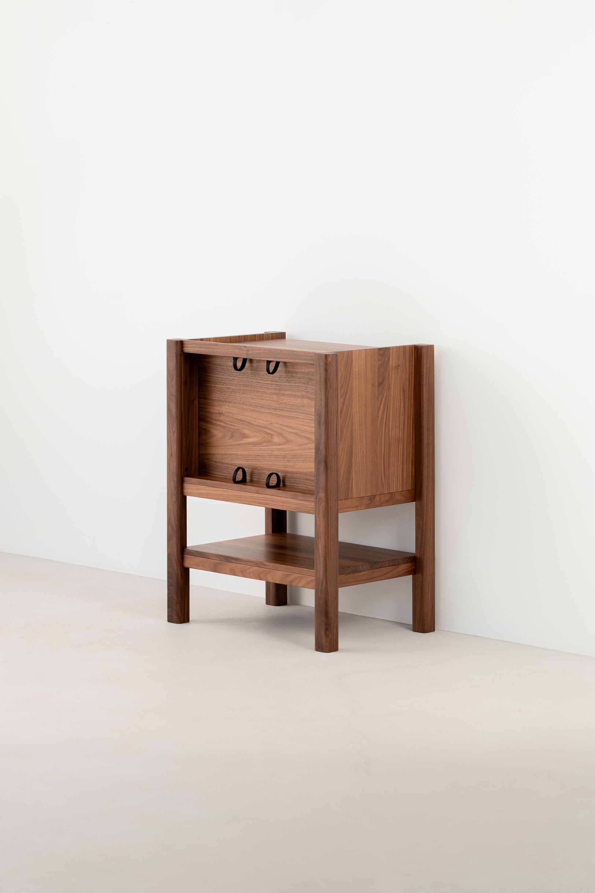 Wooden side table with an open shelf and a partially enclosed top, against a plain white wall.
