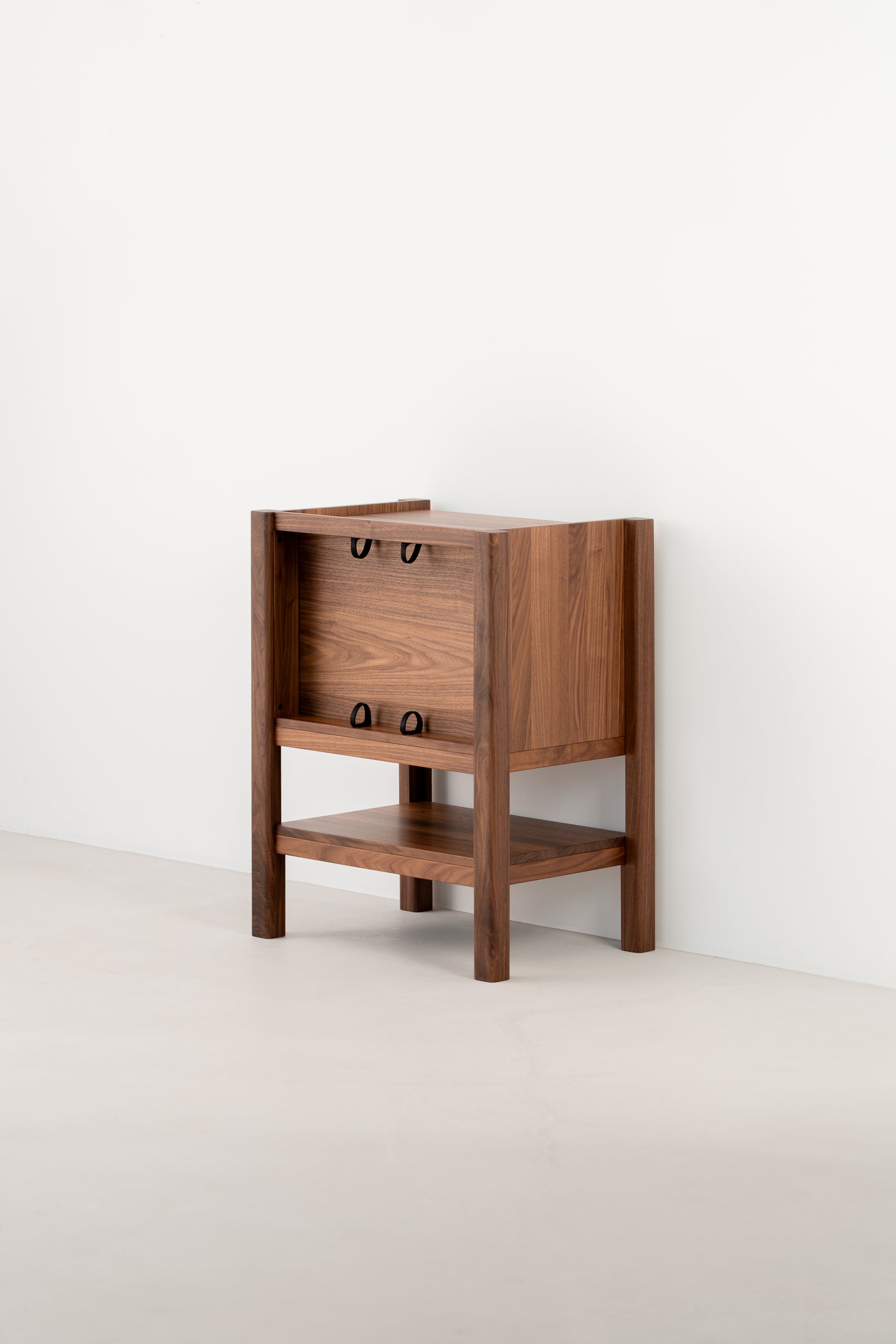 Wooden side table with an open shelf and a partially enclosed top, against a plain white wall.