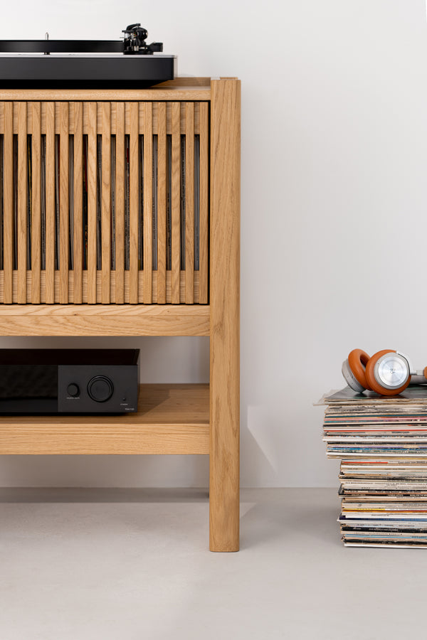 Wooden cabinet with a turntable, a receiver, and stacked vinyl records with headphones on top.