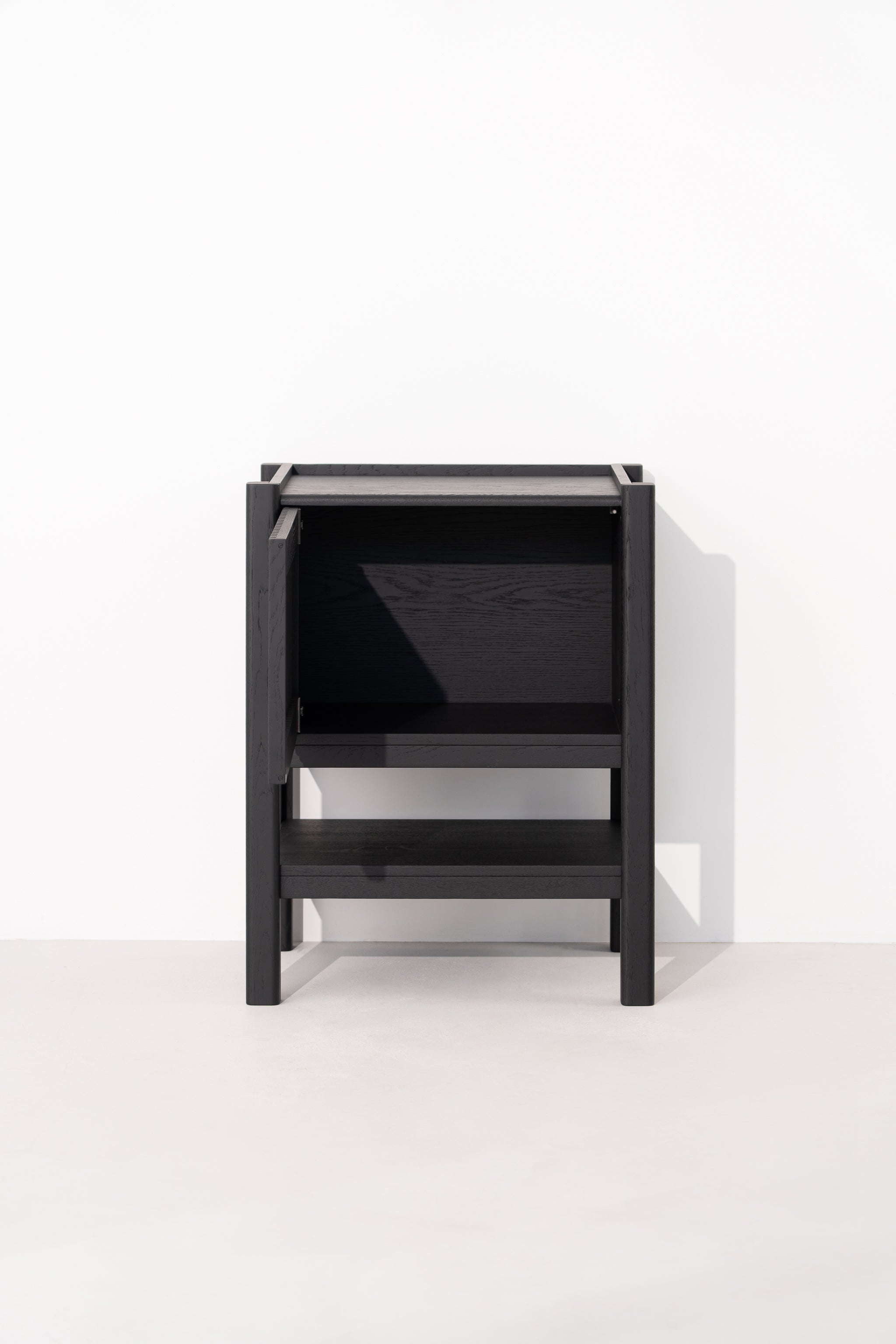 Black wooden cabinet with an open door and shelf on a white background.