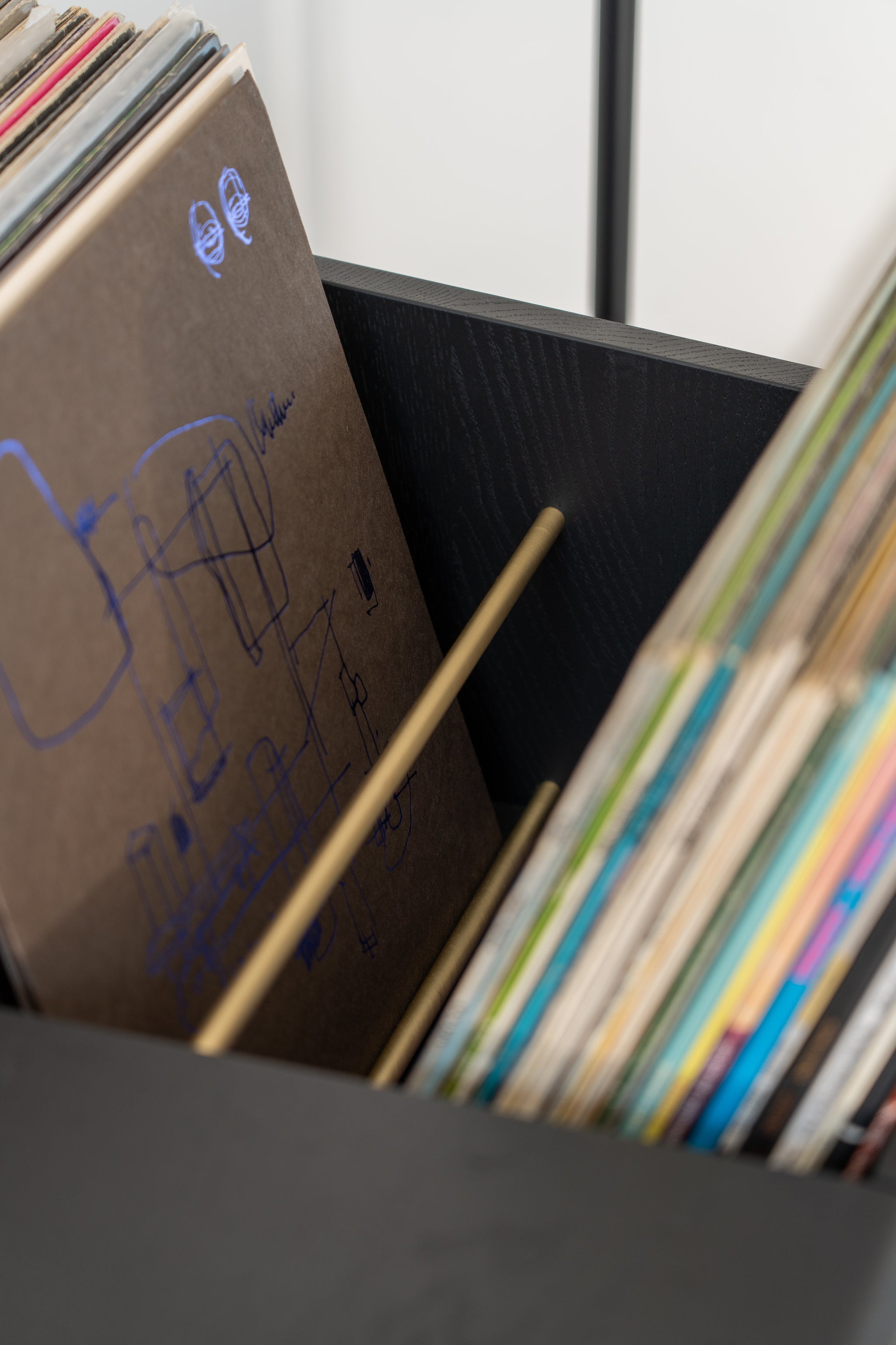 Vinyl records in a black storage crate with a visible album featuring blue line art.