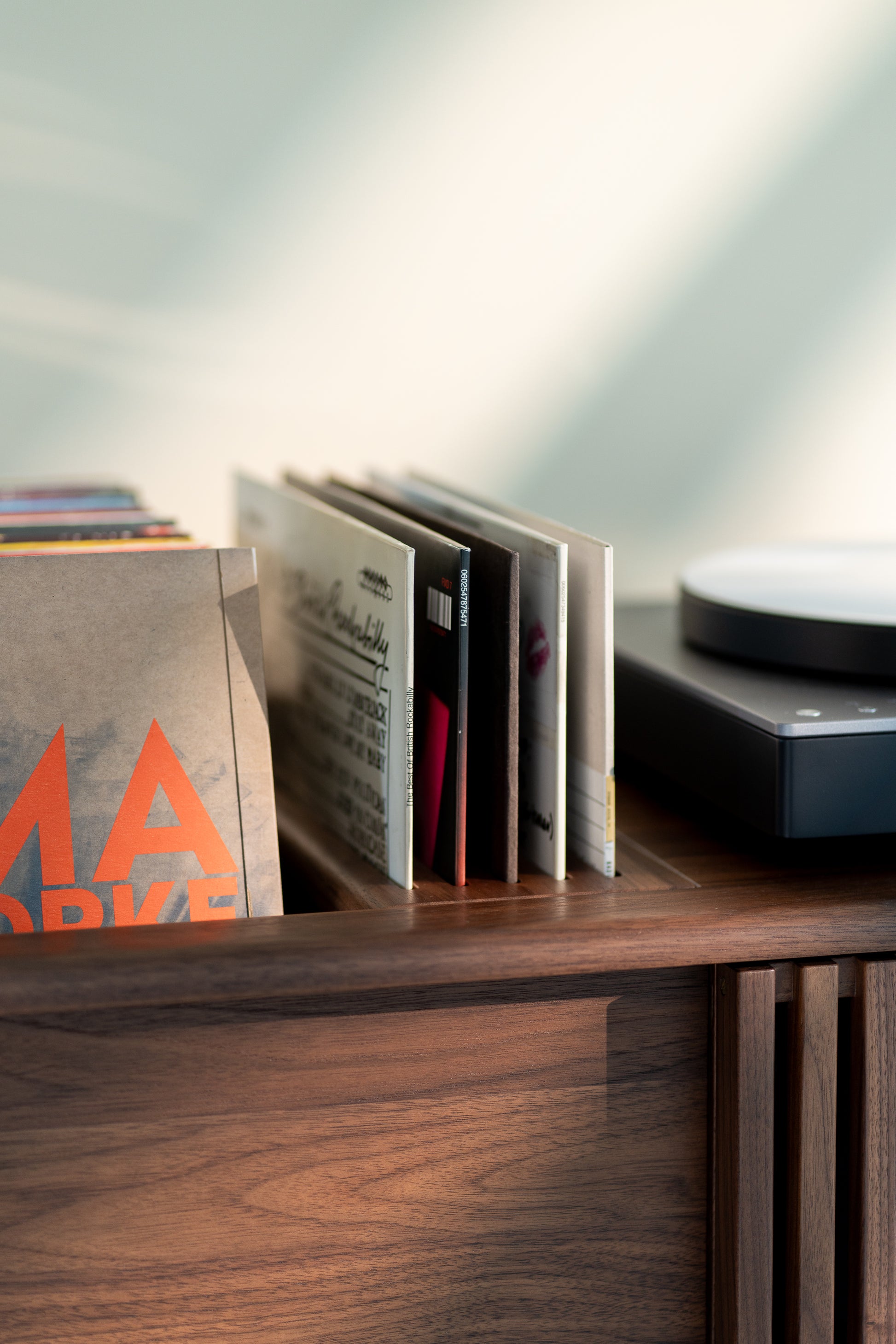 Records in a wooden shelf next to a closed turntable.