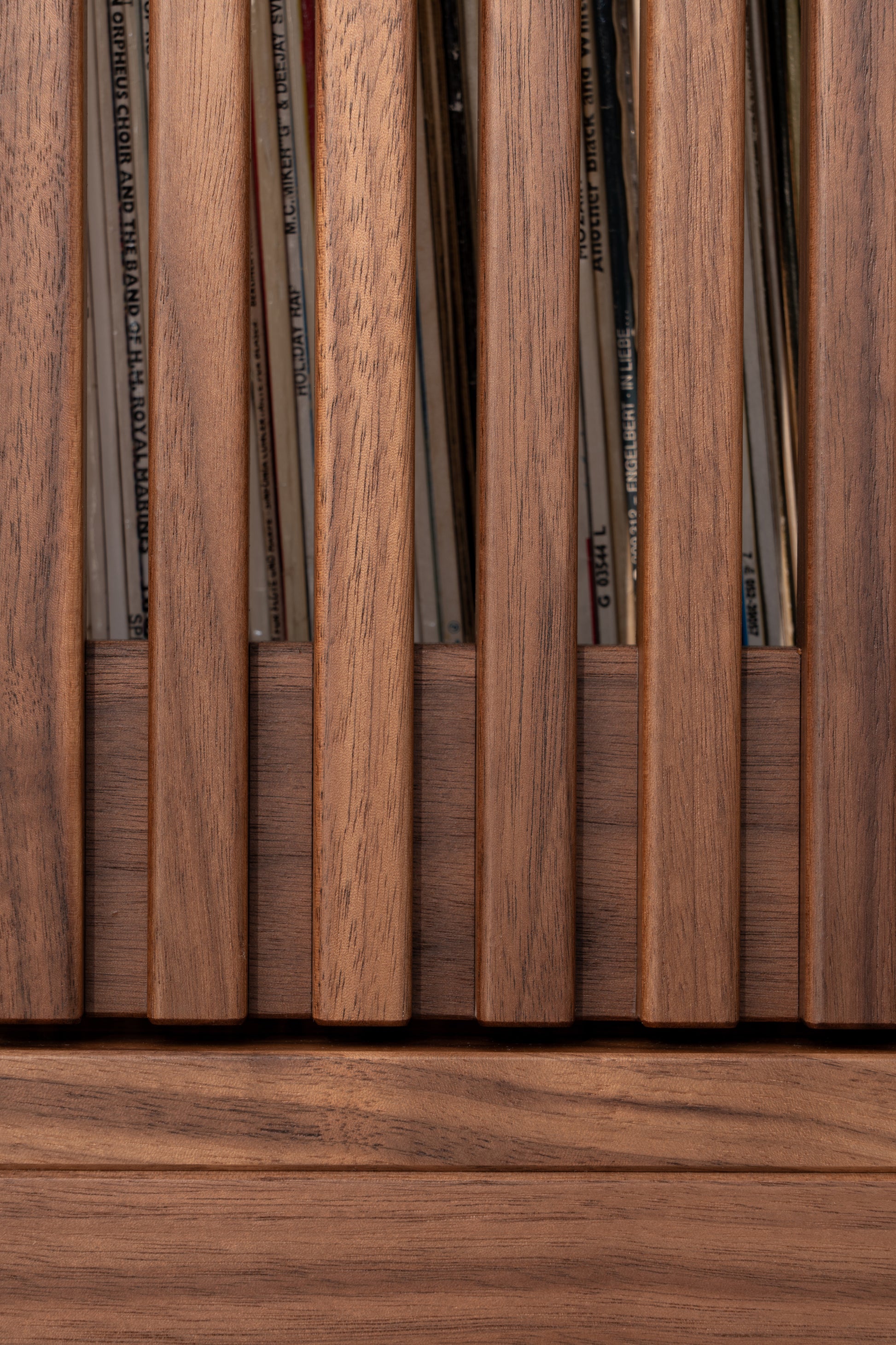 Close-up of wooden slats with vinyl records visible between them.
