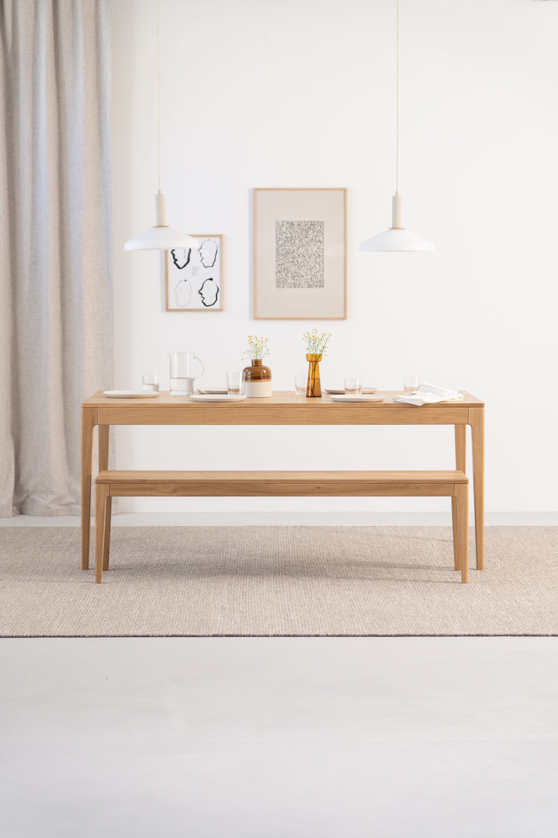 Minimalist room with a wooden bench, framed art on the wall, and a checkered blanket.