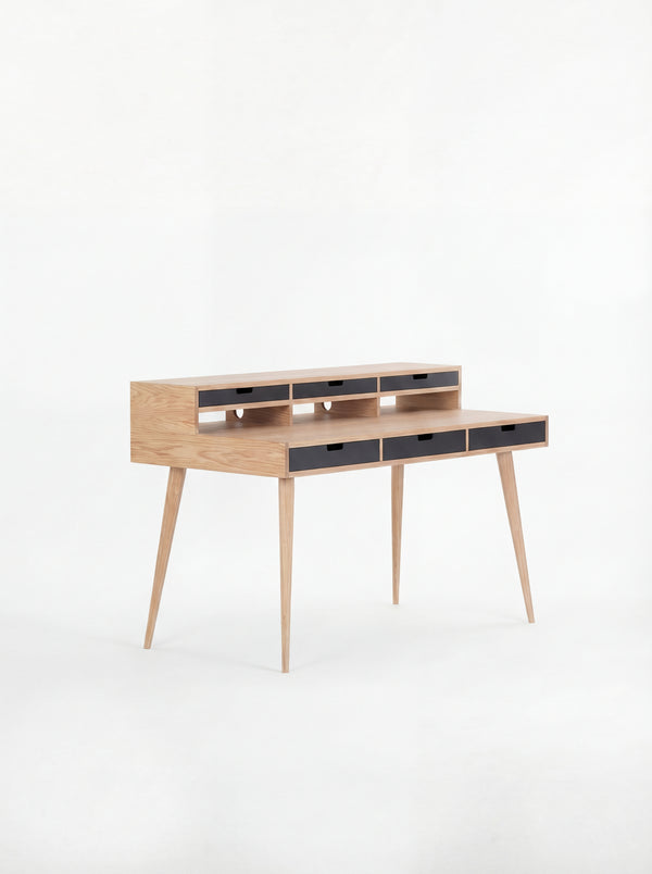 Wooden writing desk with slim legs and multiple drawers, set against a white background.