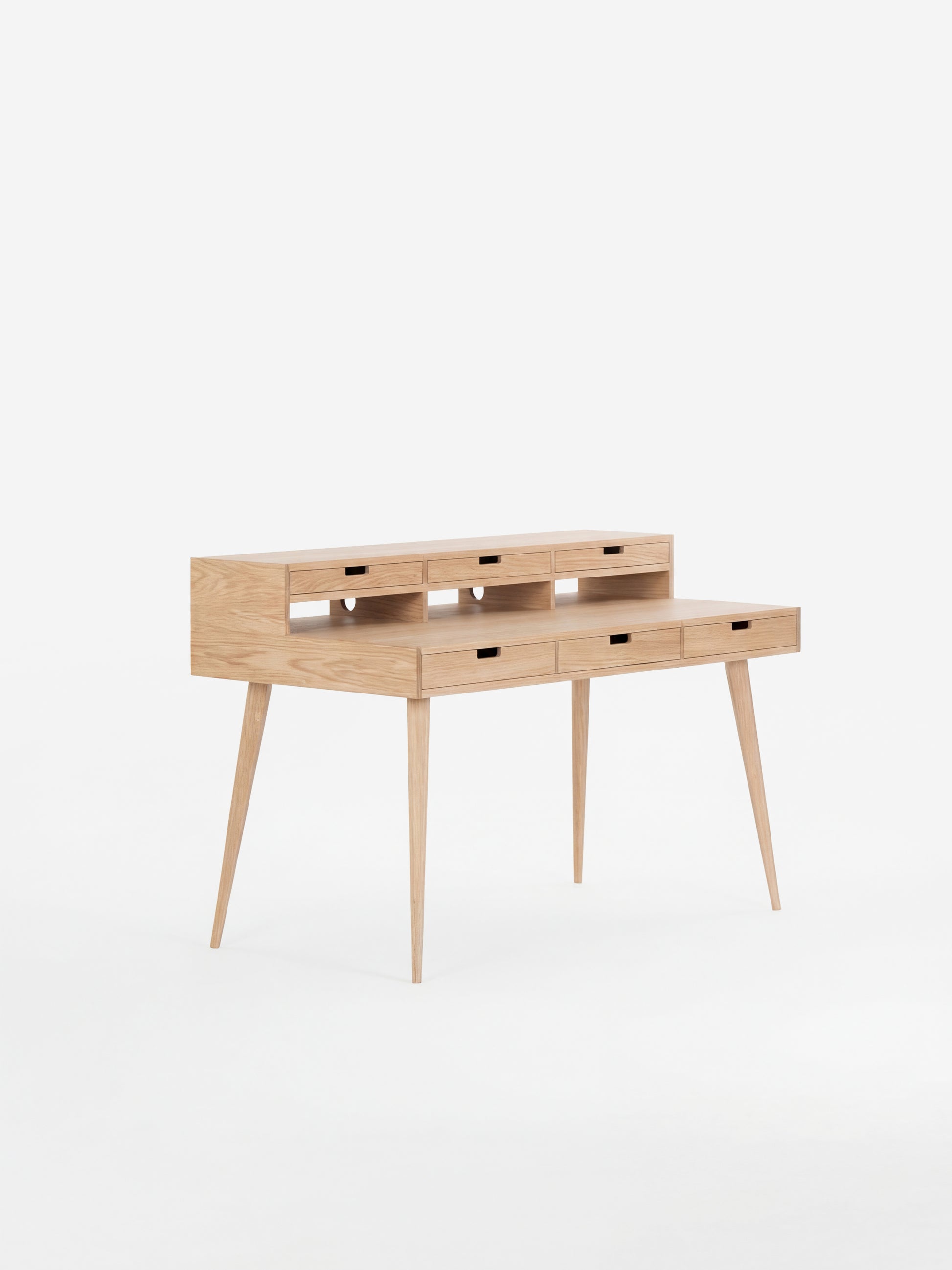 Wooden writing desk with slim legs and multiple drawers, set against a white background.