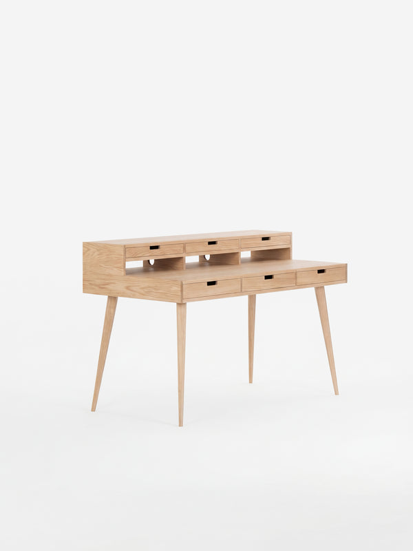 Wooden writing desk with slim legs and multiple drawers, set against a white background.
