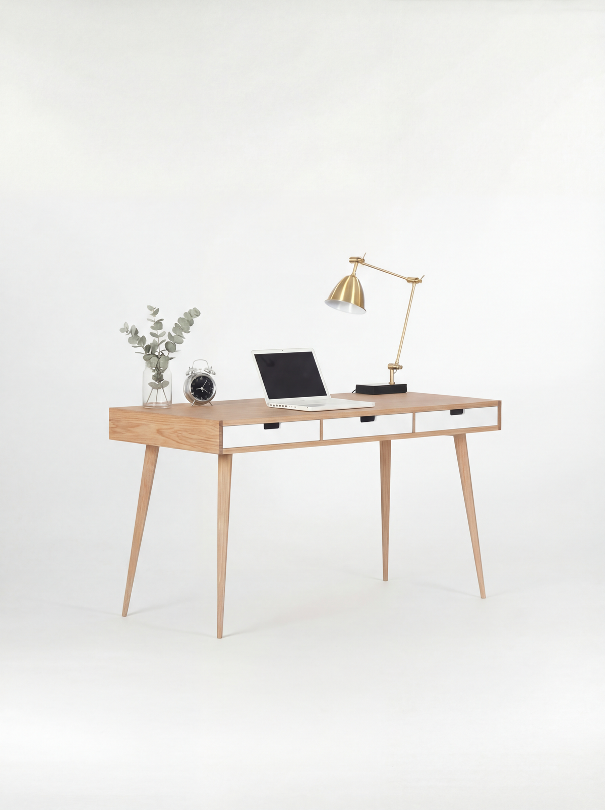 Angled HEIM 140 desk in oak wood with three white drawer fronts, a laptop and eucalyptus on top