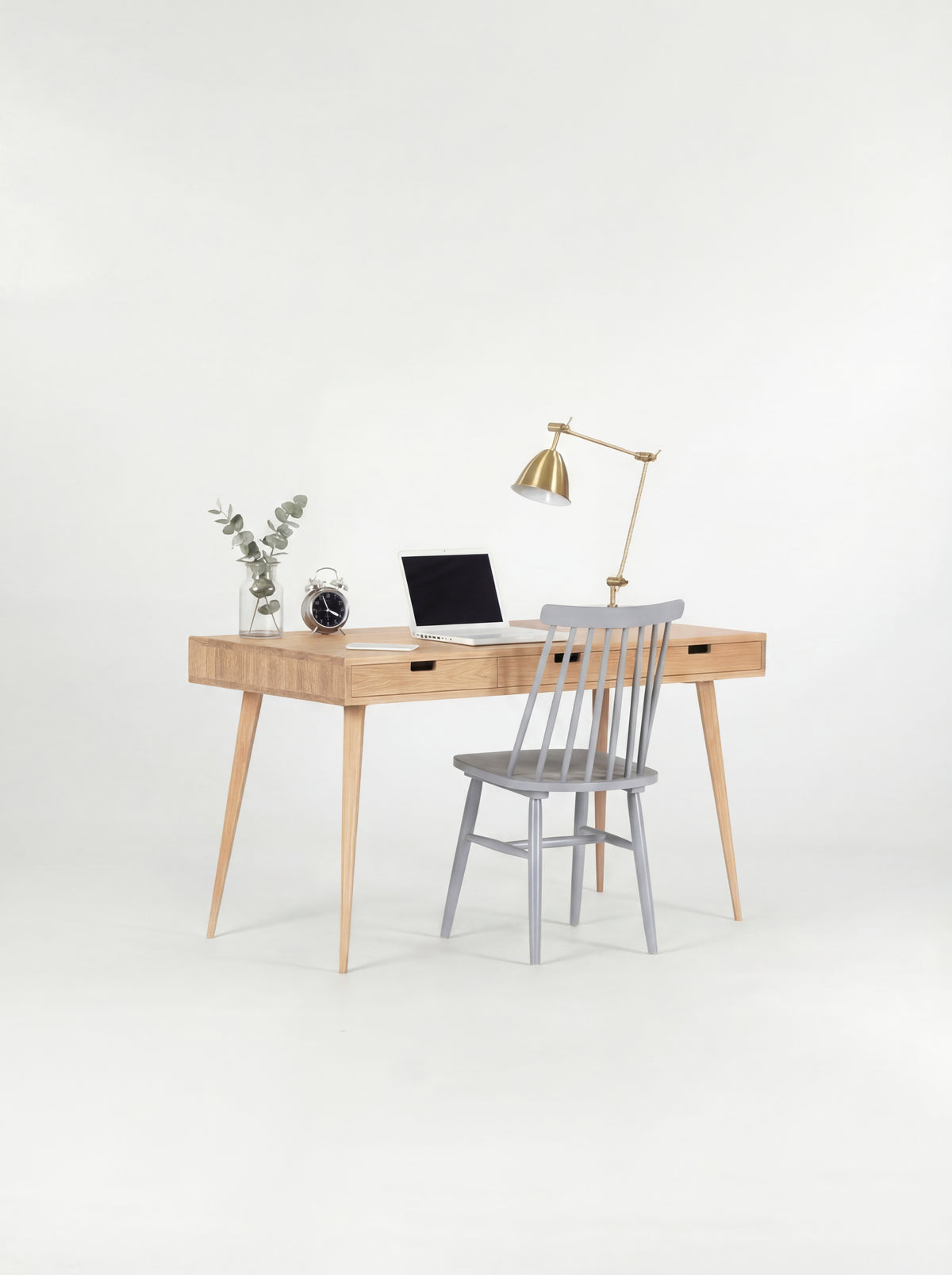 HEIM 140 desk in solid oak with a grey spindle chair pulled up, a laptop and eucalyptus on top