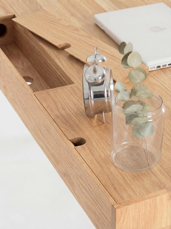 HEIM 140 desk in solid oak, overhead close-up of a raised cable flap and a round hole in the compartment below