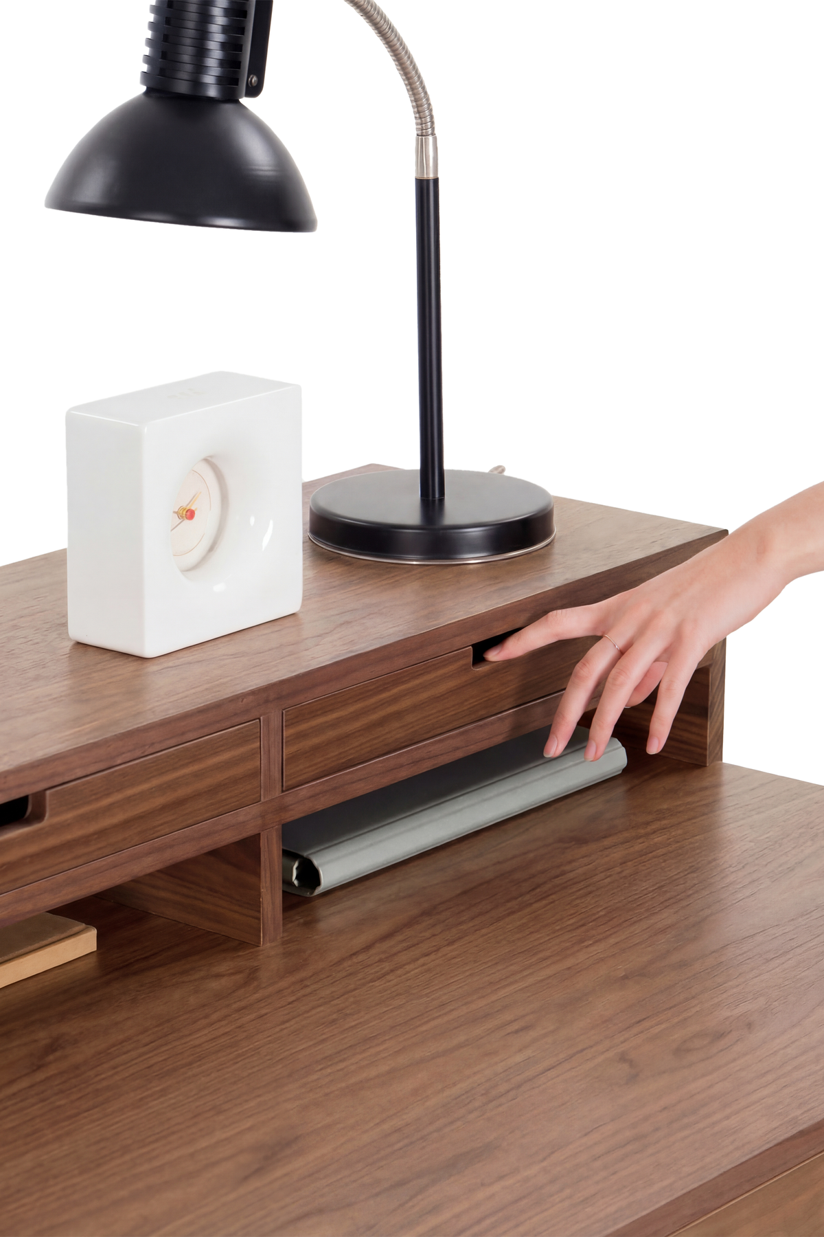 Close-up of a hand pulling a hutch drawer open on the HEIM 140 in solid walnut, with a rolled gray item below