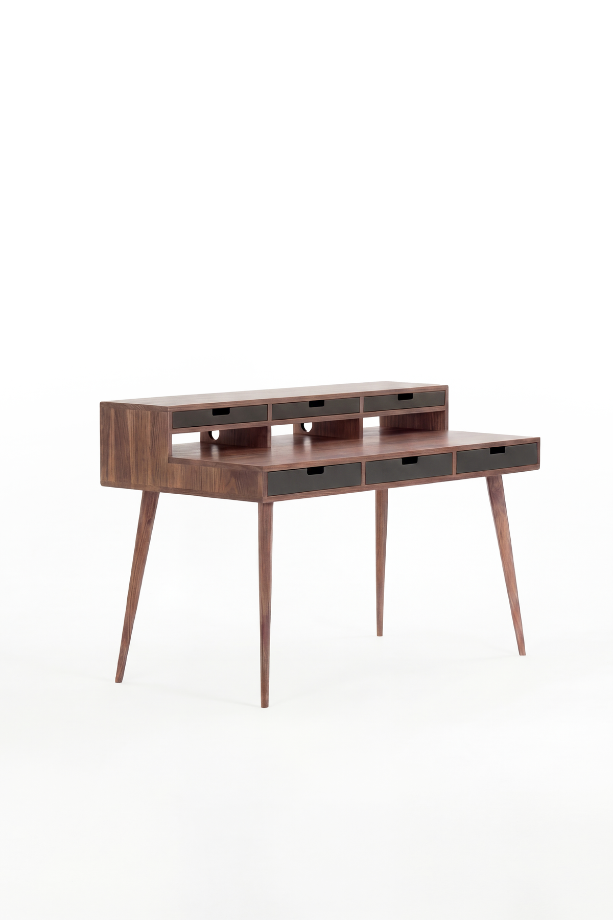 Empty HEIM 140 desk in solid walnut, shown at an angle with six black drawer fronts on a white background