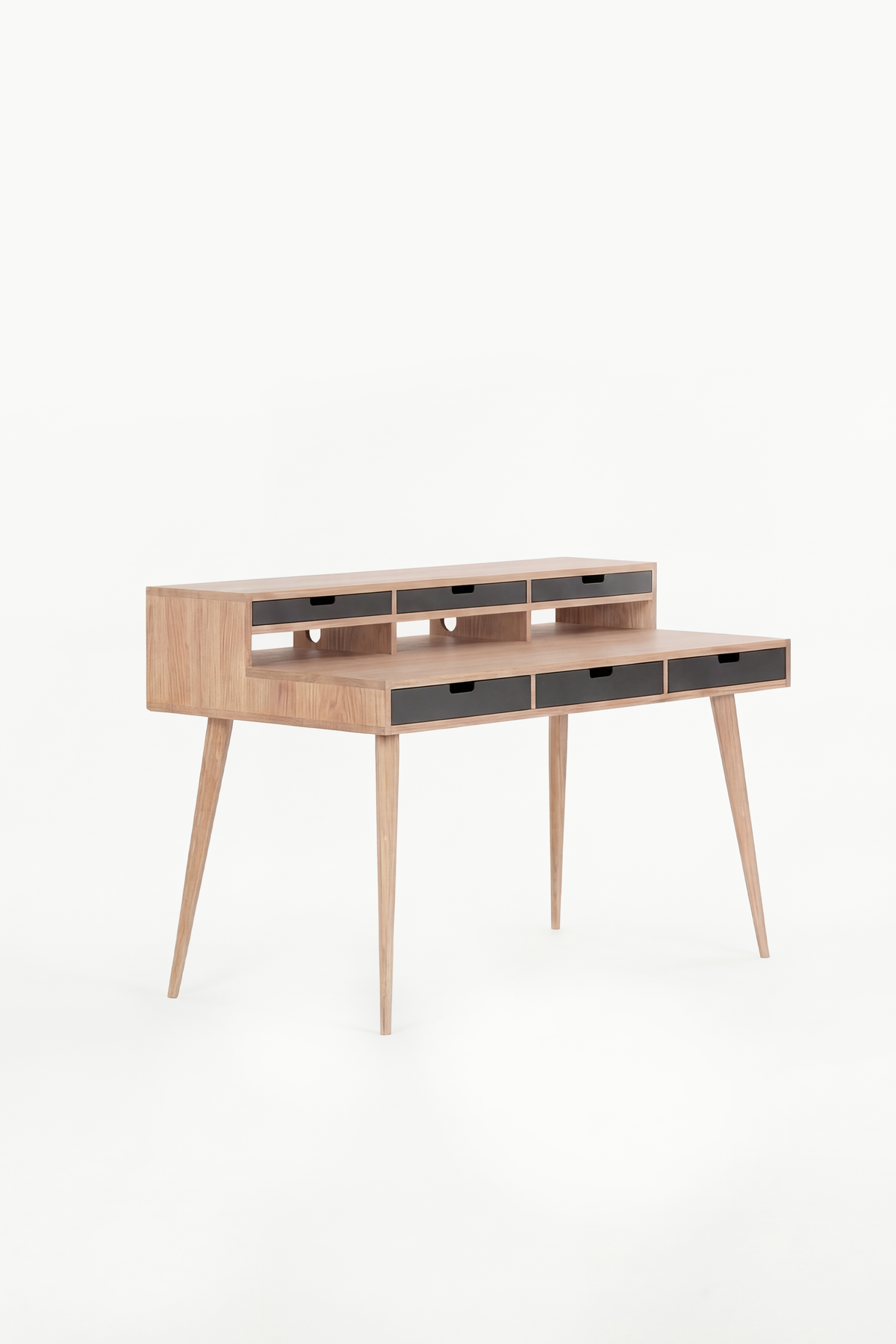 Three-quarter view of the HEIM 140 in solid oak, with six black drawer fronts across the desk and hutch