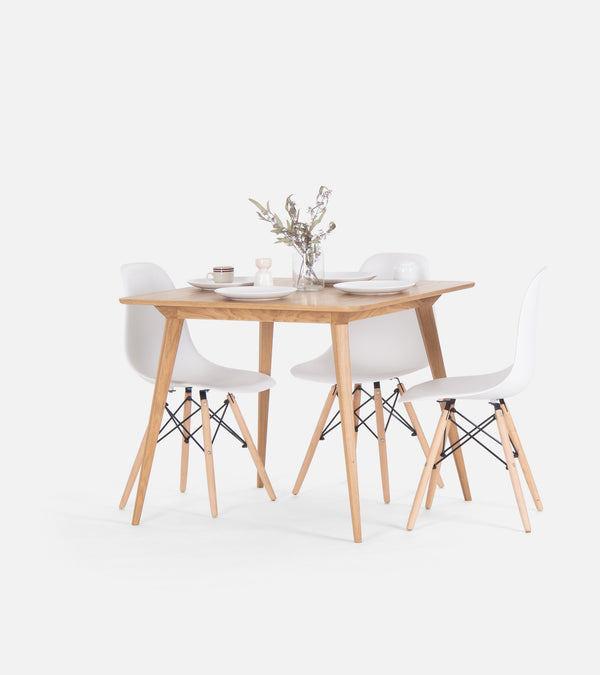Minimalist dining set with a wooden table, four white chairs, and a vase with flowers.